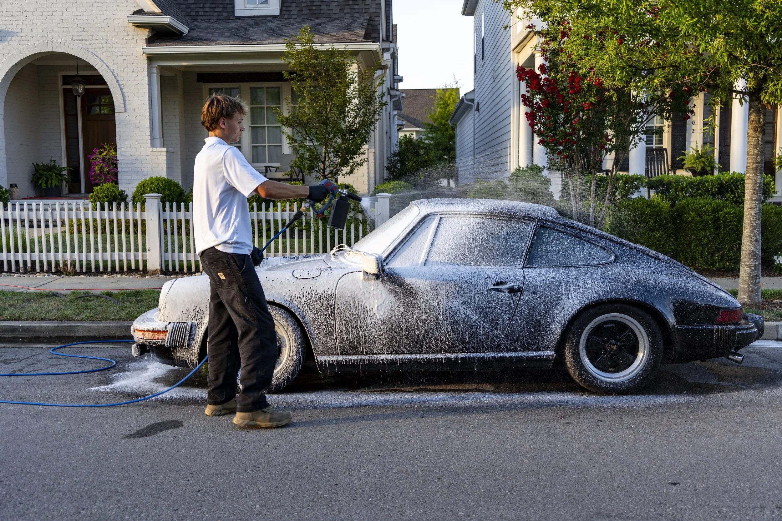 Classic black Porsche receiving foam bath — Reflections Perfection luxury car detailing on suburban street in Franklin, TN.