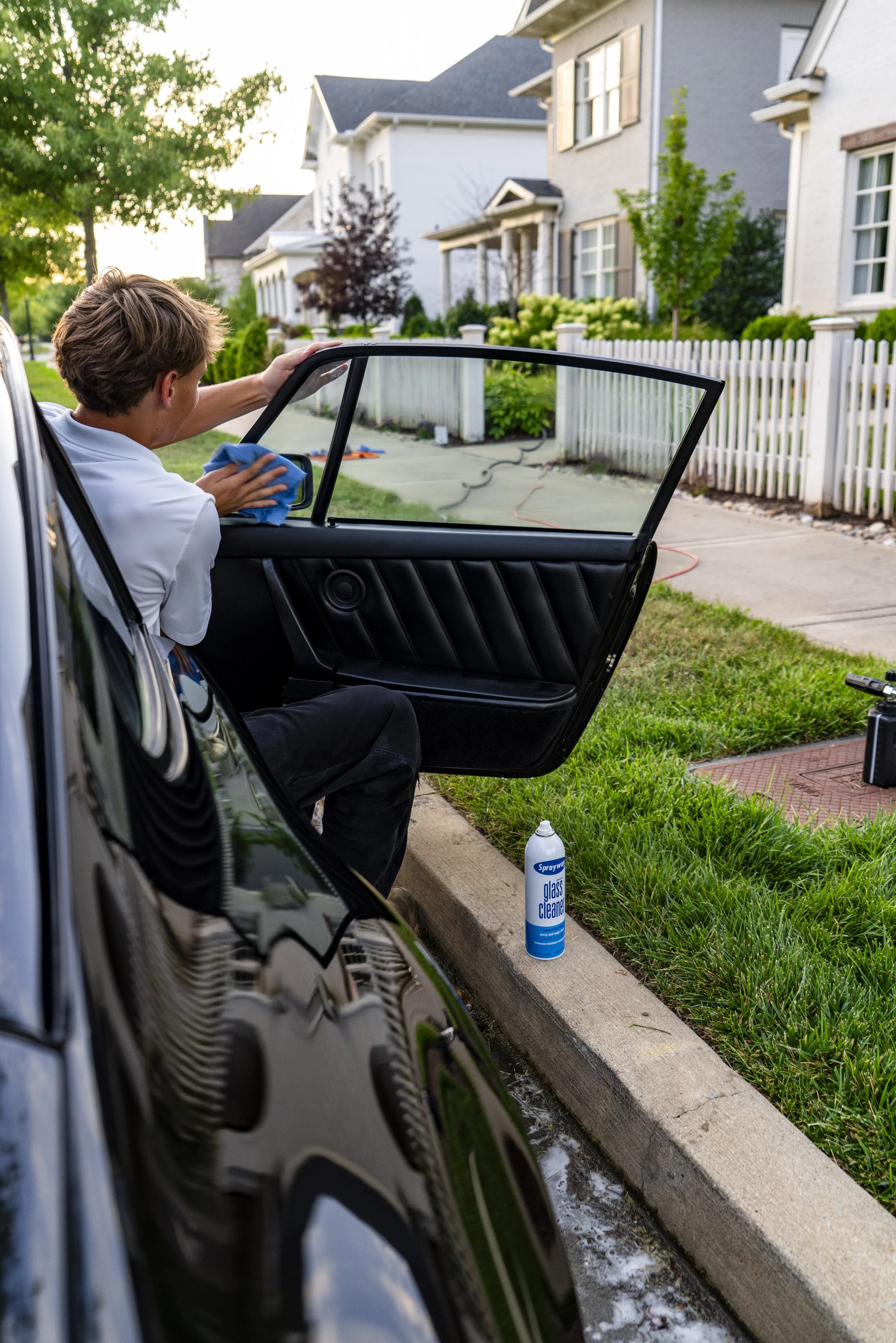 Glass cleaner and cloth next to car window — Reflections Perfection’s spotless window detailing service.