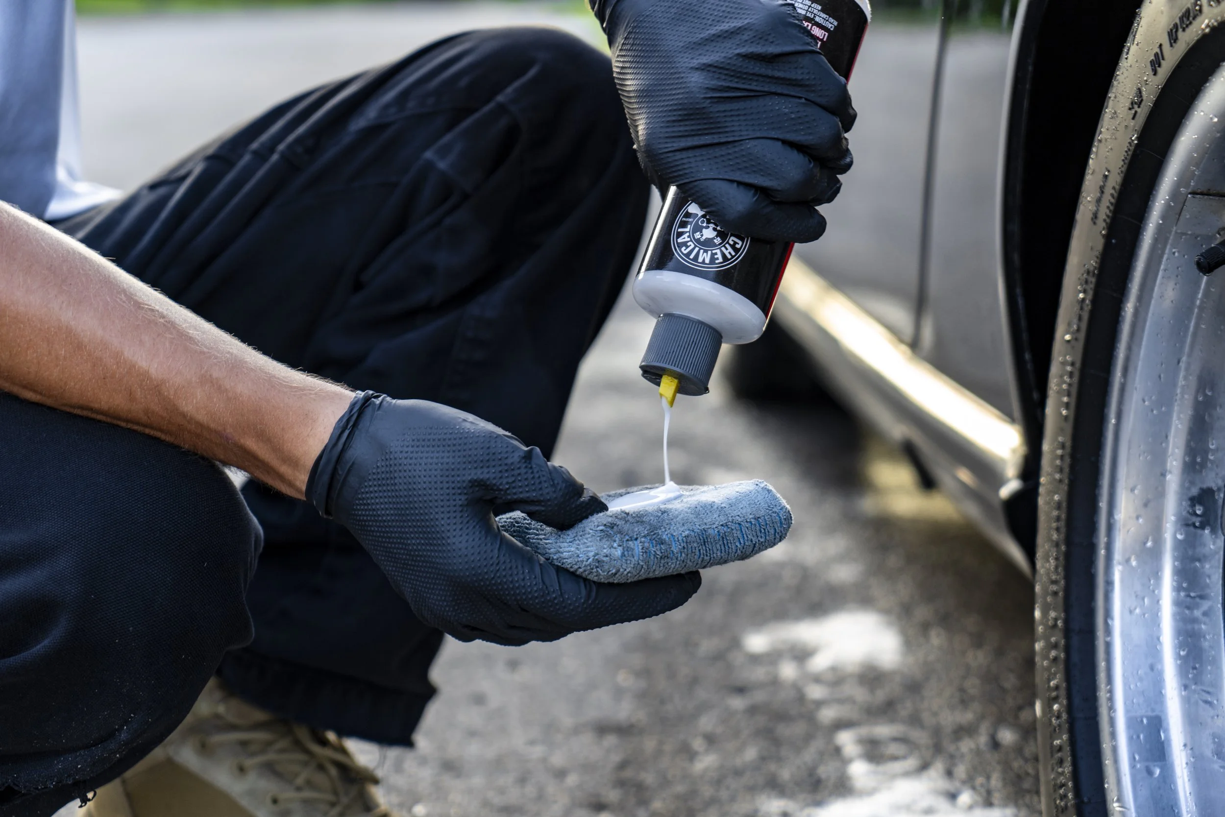 Spray bottle and cloth in use — close-up of wheel and tire detailing by Reflections Perfection technician.
