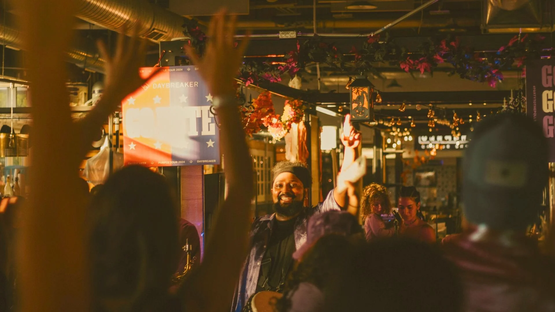 Event host with an enthusiastic crowd. Everyone's arms are raised, the morning light is golden shining through from the sides.
