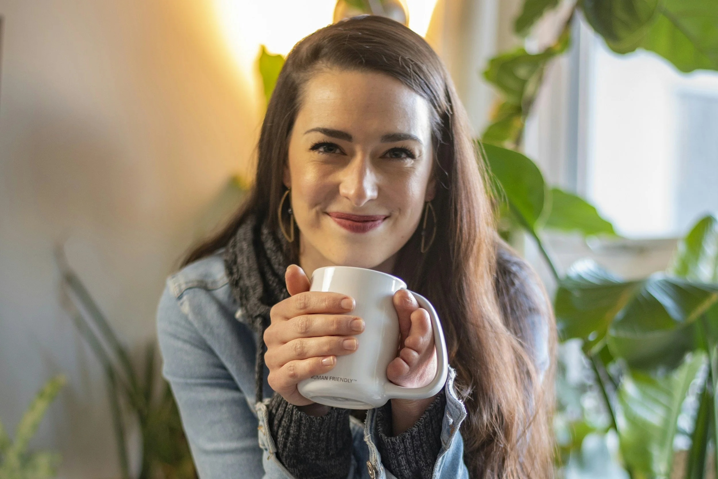 Mujer sonriente sujetando una taza de té con las dos manos, mostrando que en su mano izquierda le hacen falta algunos dedos. Ejemplo de resiliencia y transformación.