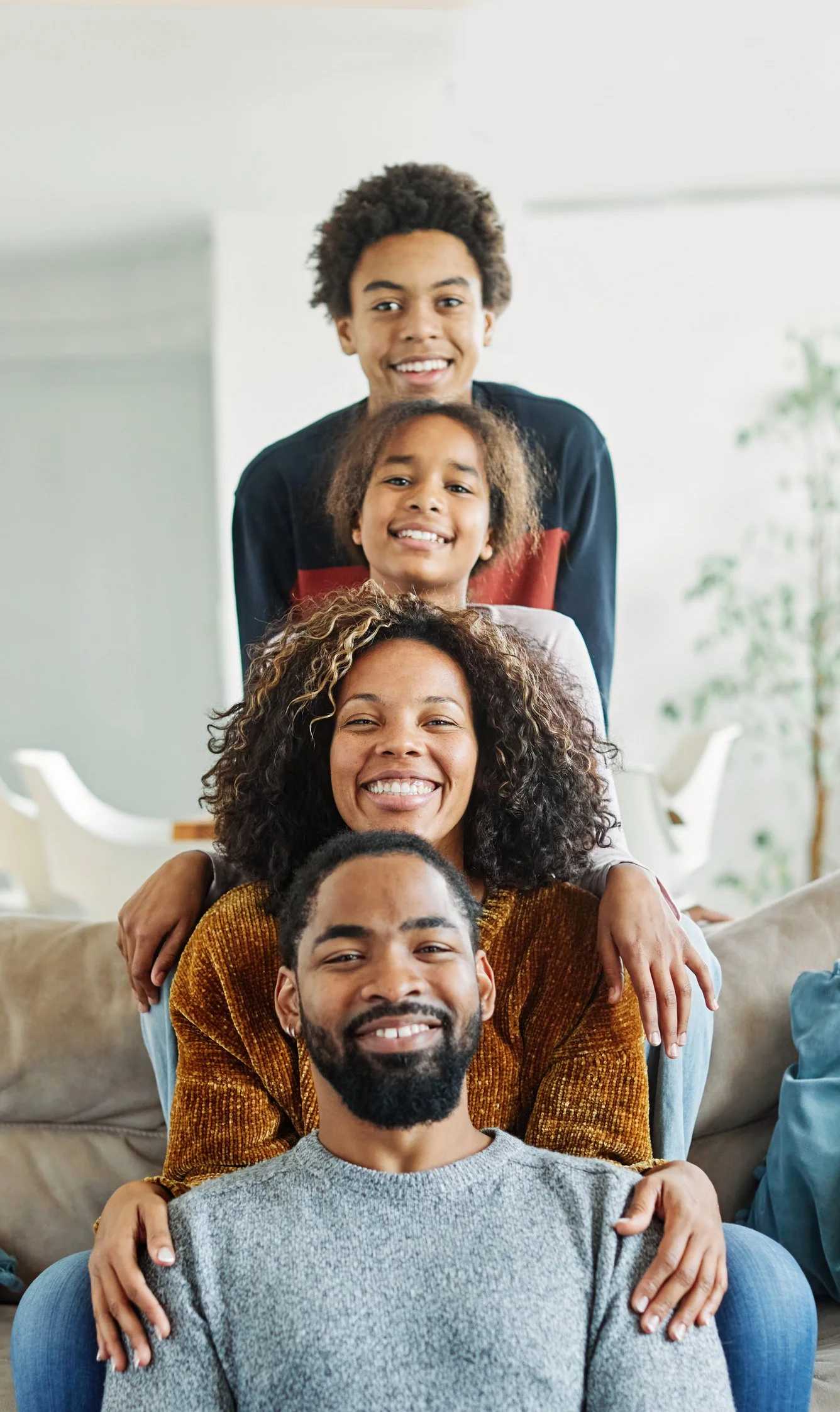 No es terapia de familia en español. Es consulta educativa en español. Una familia multicultural y sonriente en una sala de estar, disfrutando al máximo su vida, tras recibir información crucial.