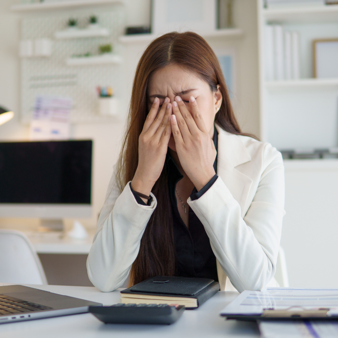 woman rubbing her eyes at her desk while struggling to focus