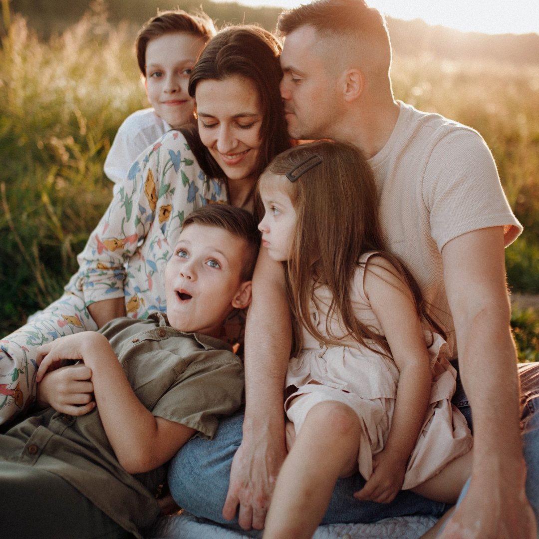 A family sitting on the grass in front of a lake