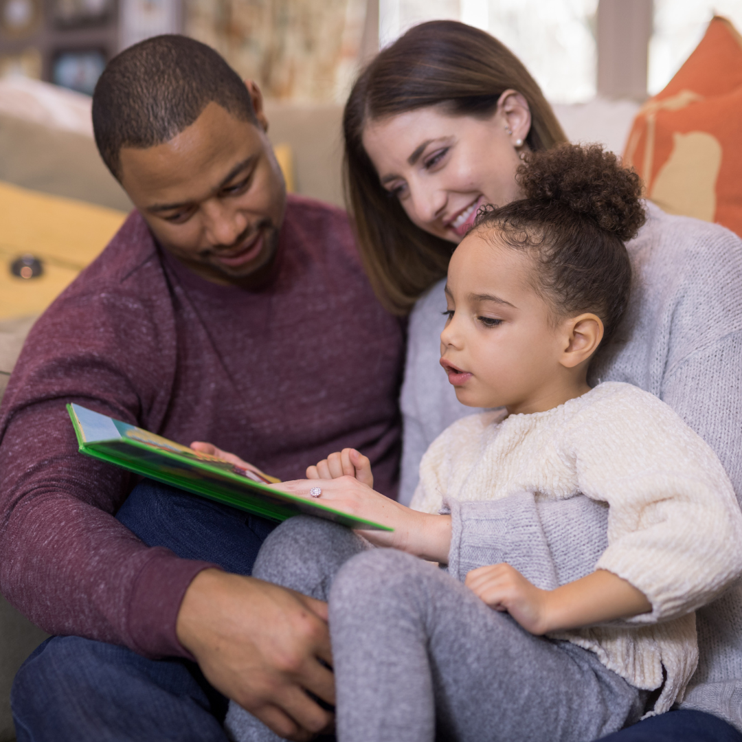 Three people sitting on a couch reading a book