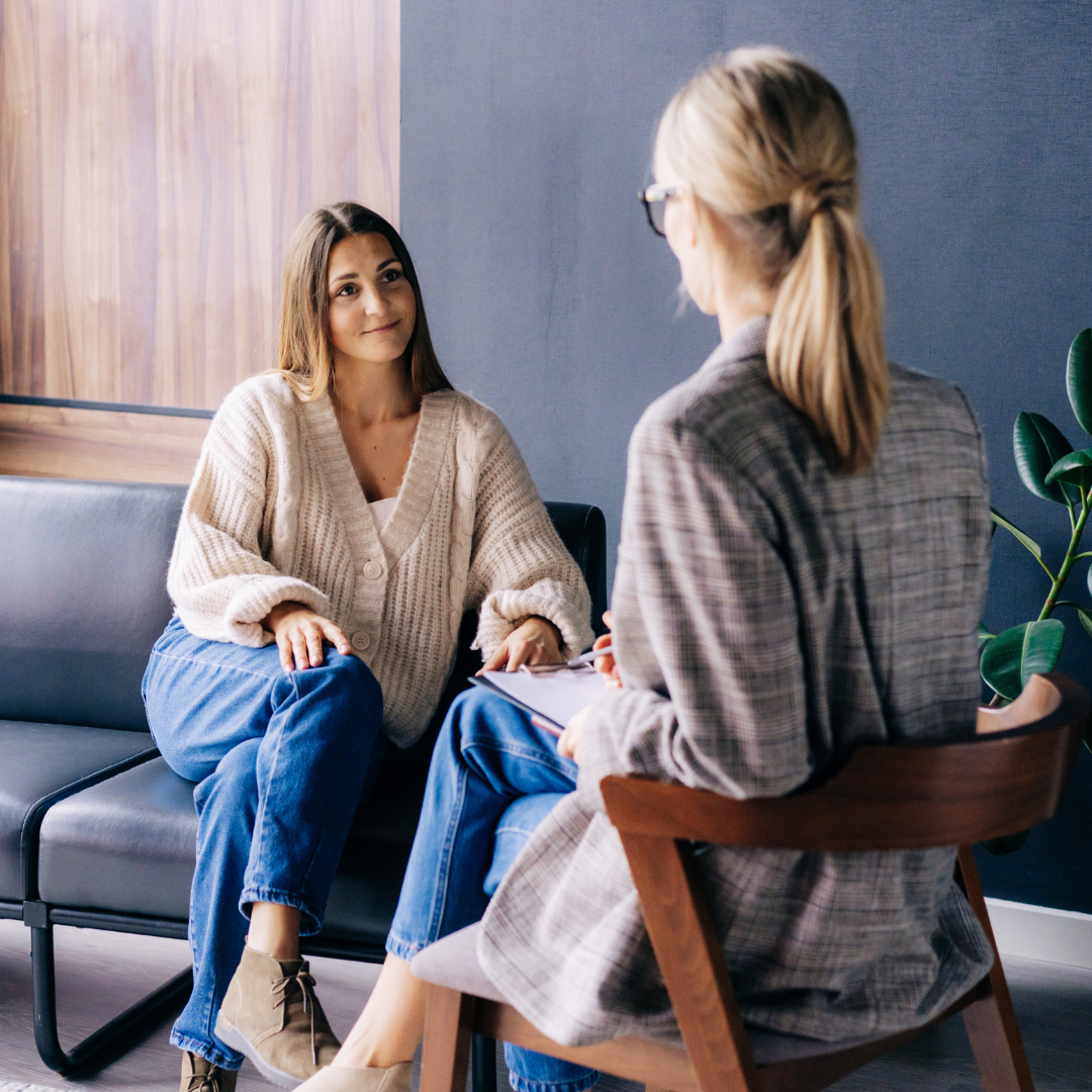 two people sitting on a couch talking to each other