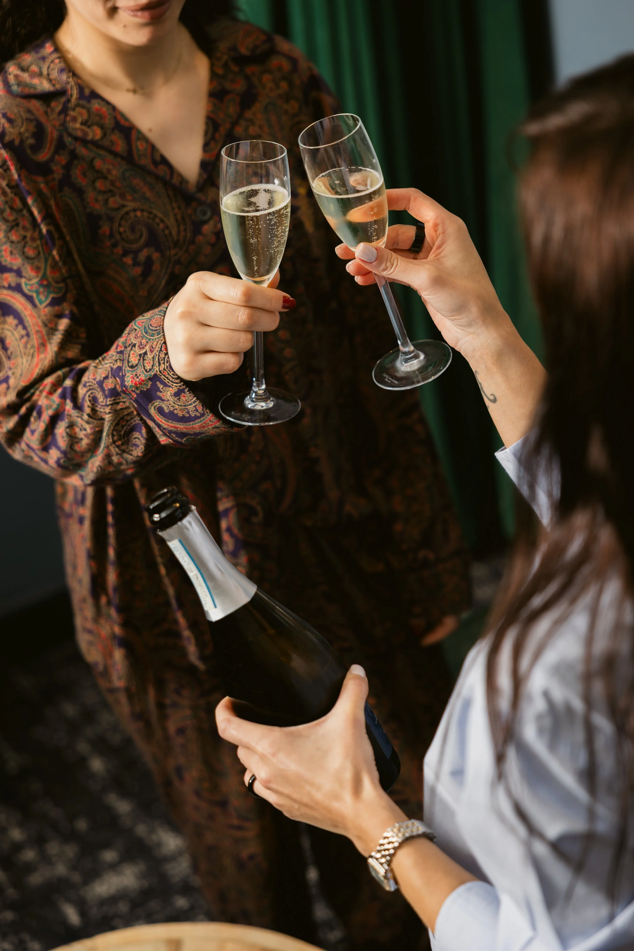Two women toasting with champagne glasses; one woman holding a champagne bottle.