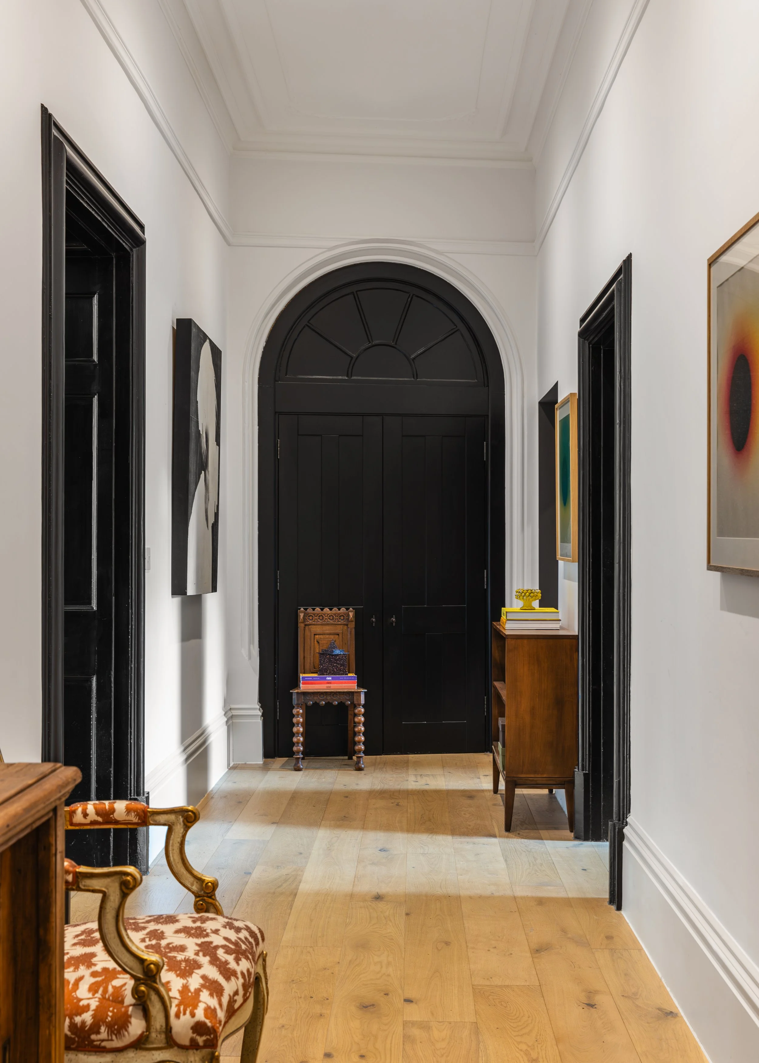 Hallway with white walls, black door at the end, and framed art on the walls.