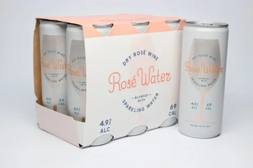 Four cans of dry rosé wine sparkling water in a pink and white cardboard holder.