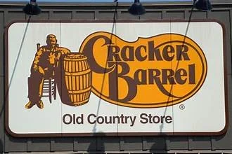 Sign for Cracker Barrel Old Country Store with a man sitting on a stool next to a large barrel
