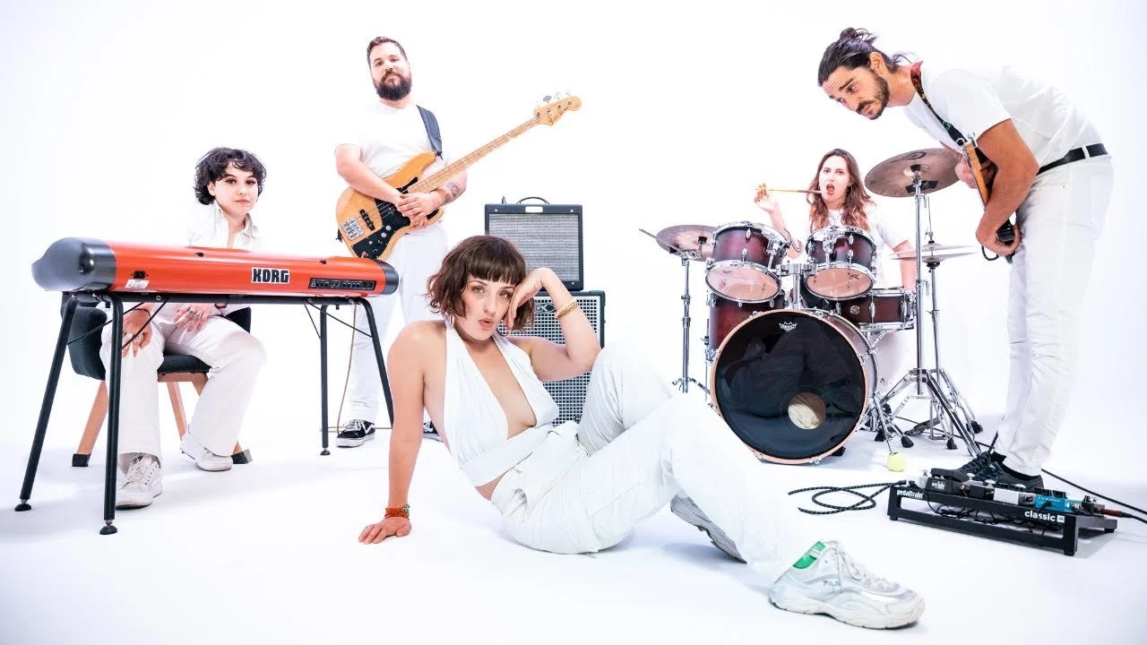 Un groupe de cinq musiciens posant avec leurs instruments dans le studio Cyclorama
