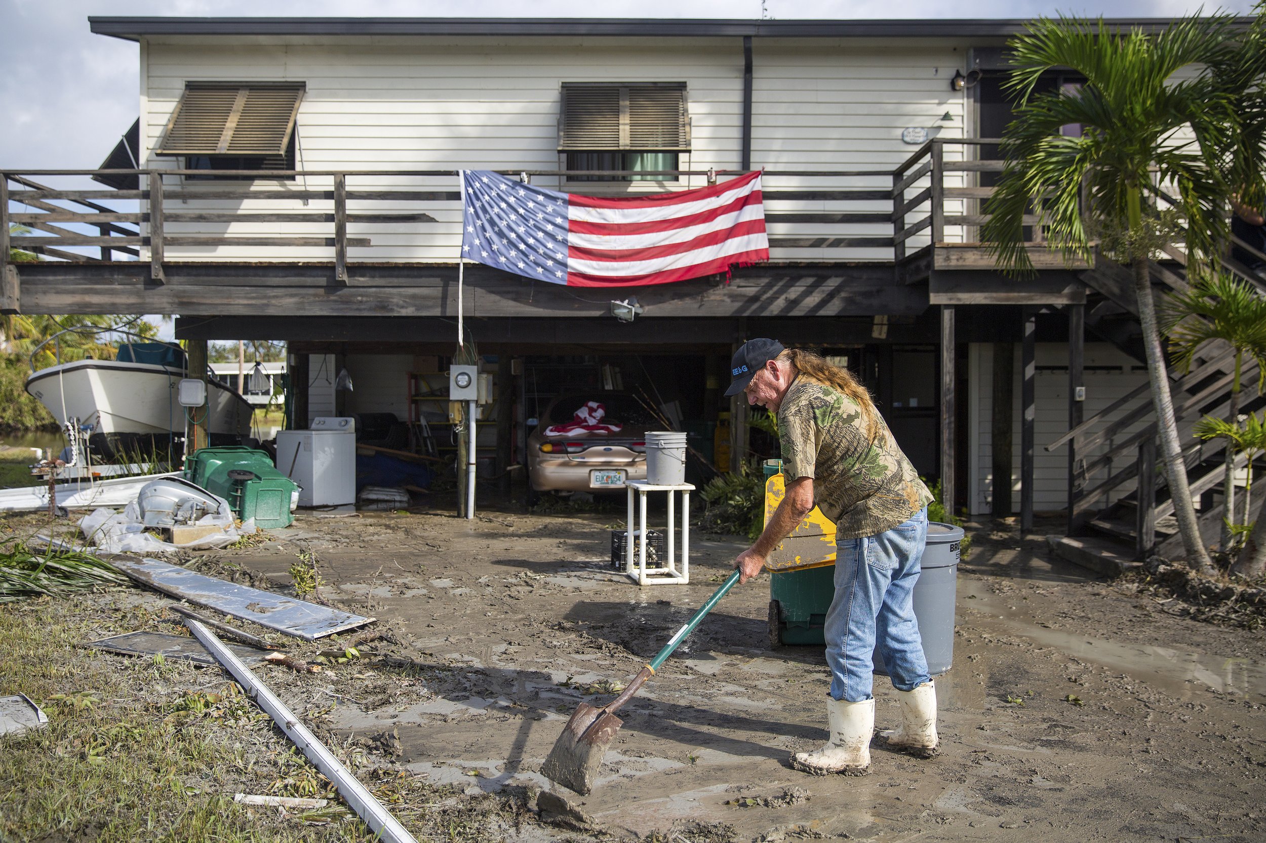 Harvey Pennell works to shovel a thick layer of mud from the driveway of his home in Plantation Island, an unincorporated area nearby Everglades City, as Collier County began picking up the pieces in the aftermath of Hurricane Irma on Tuesday, Septem