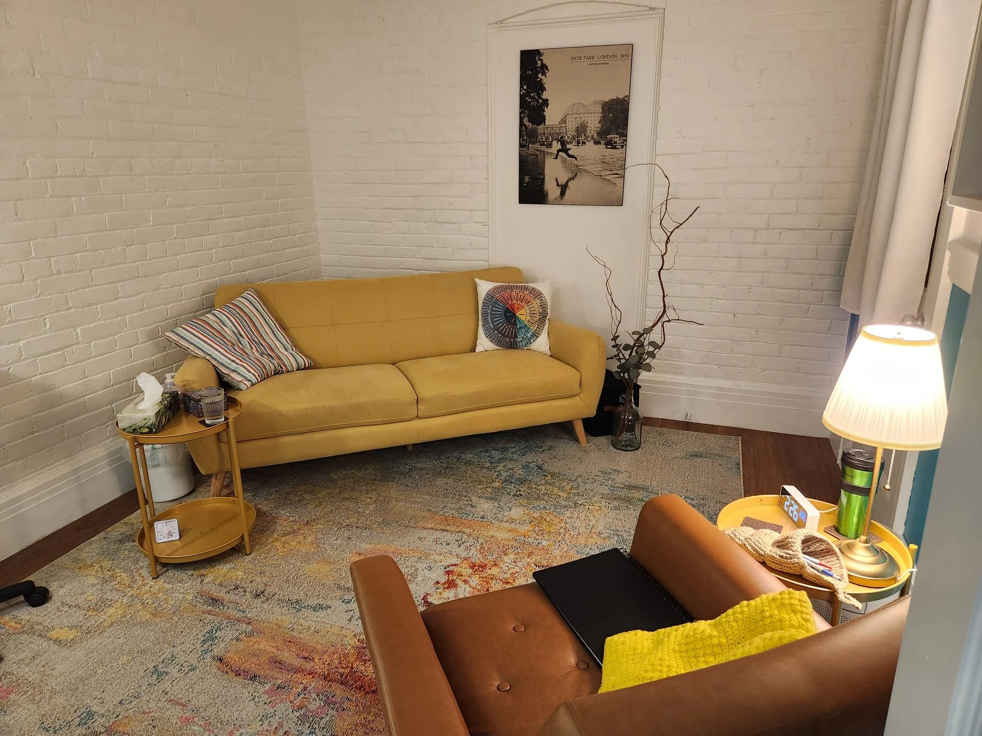 Photo of the office, with a couch facing the camera and the therapist chair's back to the view. Office decoration indicates a warm and open space