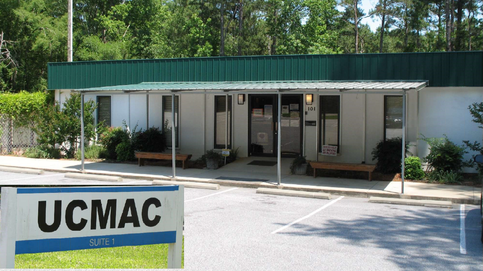 Exterior of the main UCMAC office building with a sign reading 'UCMAC', surrounded by parking spaces and greenery.