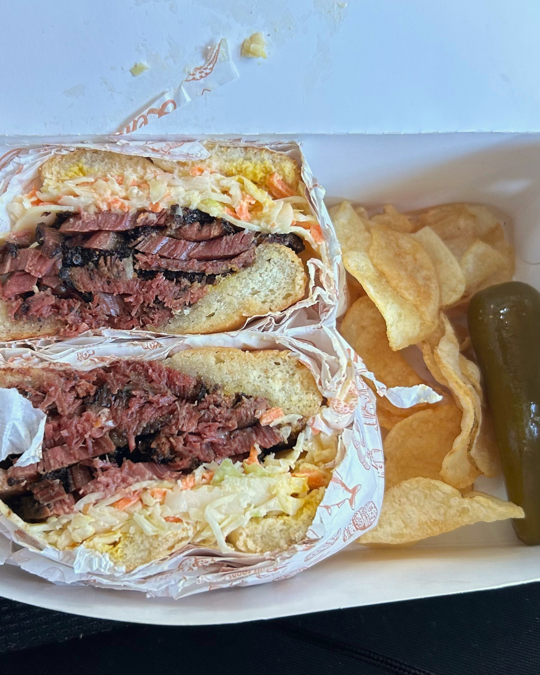 Zaidys pastrami sandwich with a side of pickles and chips