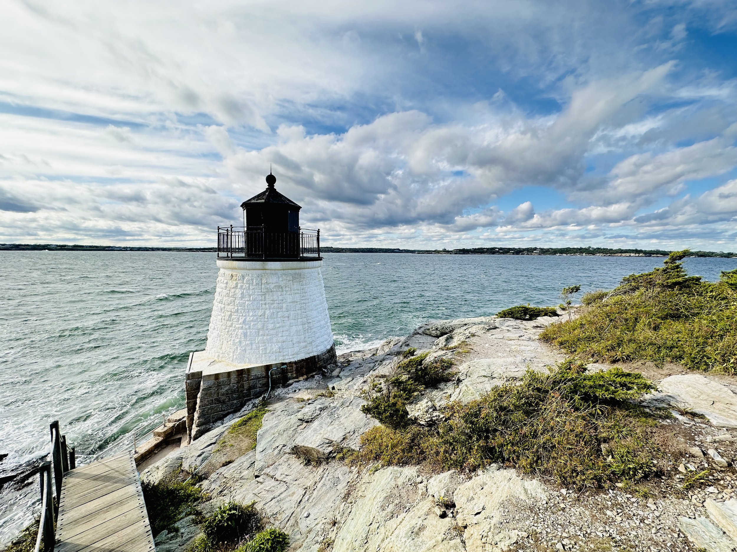 Boardwalk leading to the small, white, Castle Hill Lighthouse in Newport, RI