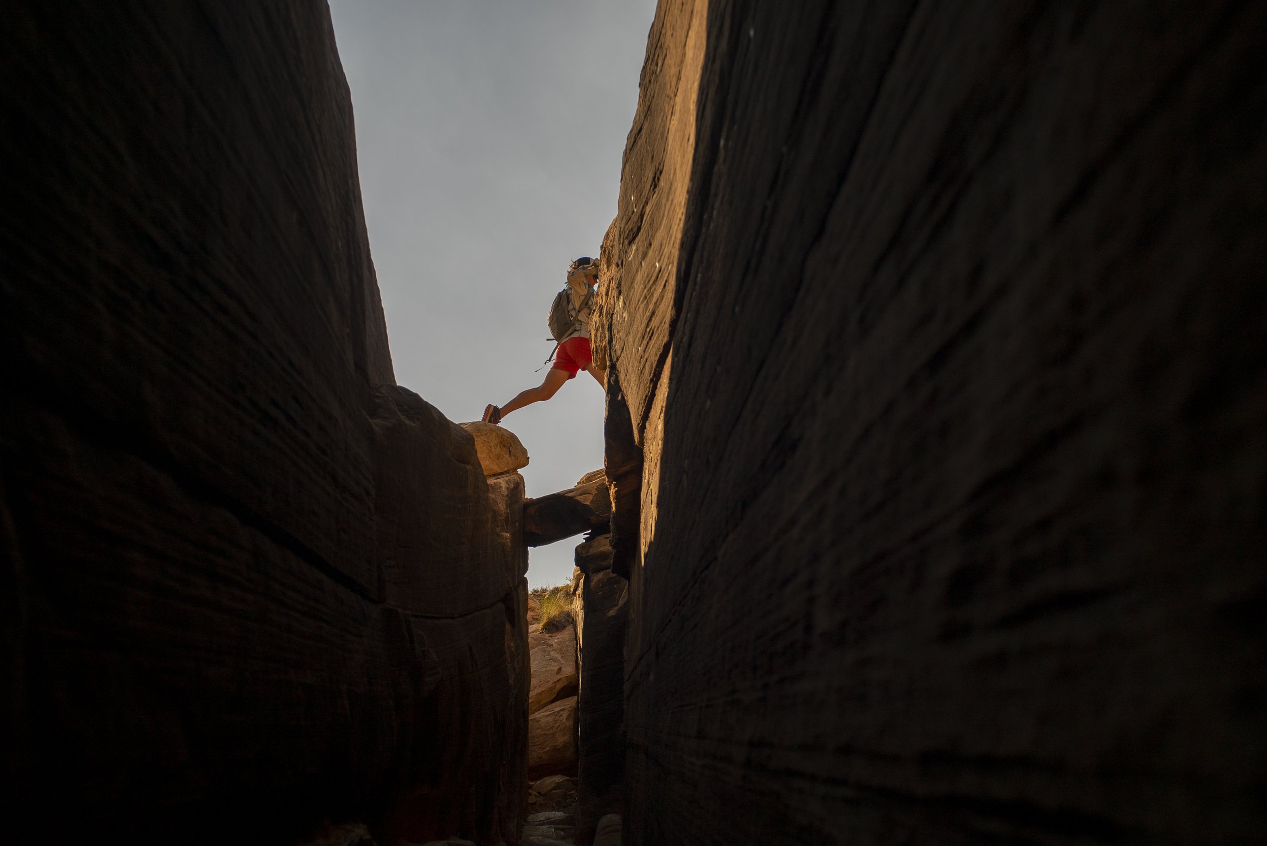 Woman stepping over a slot canyon at the Dollhouse in Canyonlands, Utah
Photo credit: Dana Romanoff