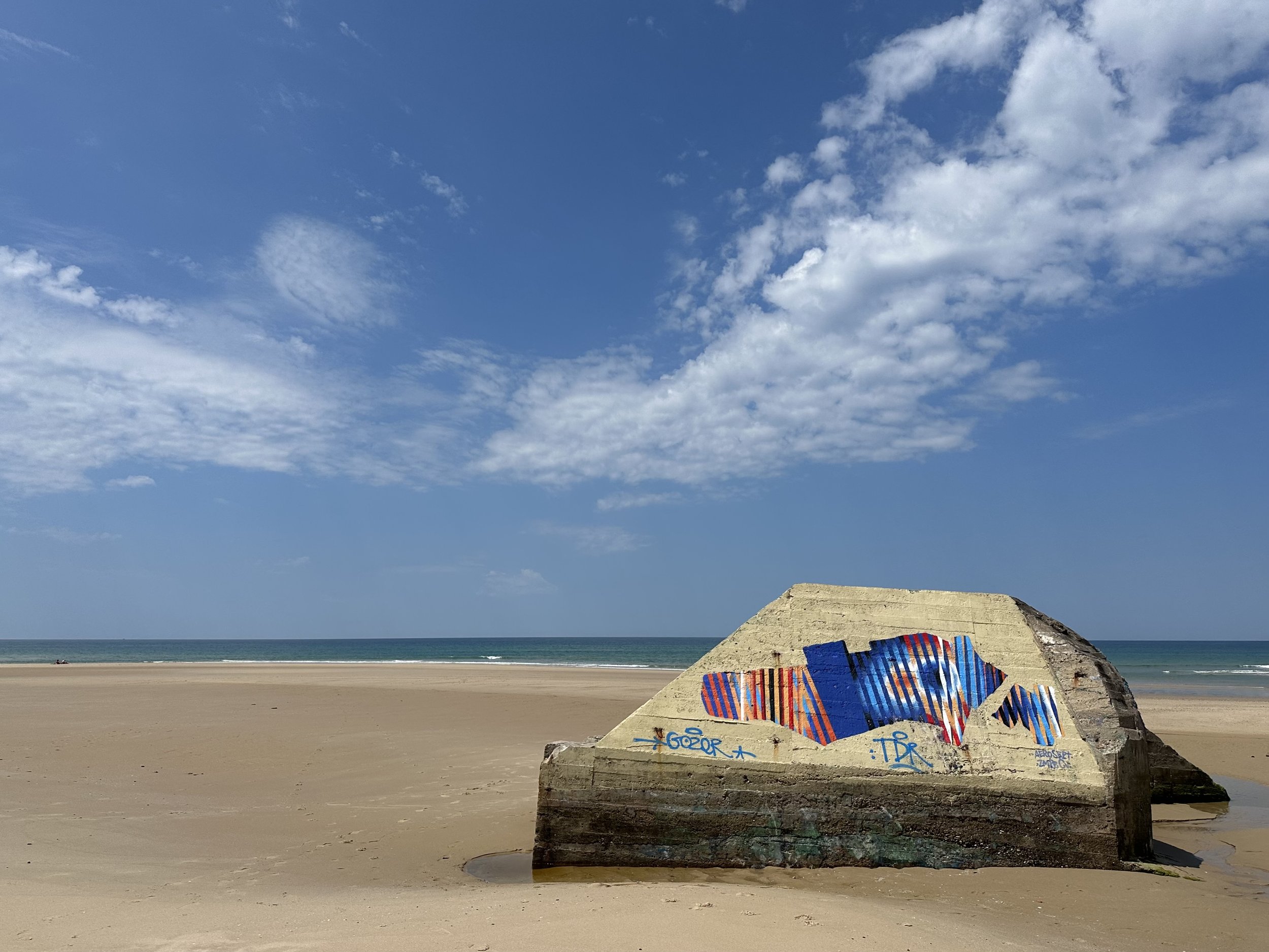 An old, concrete, WWII bunker tagged with new artwork on a beach in Plage du Pin Sec, France