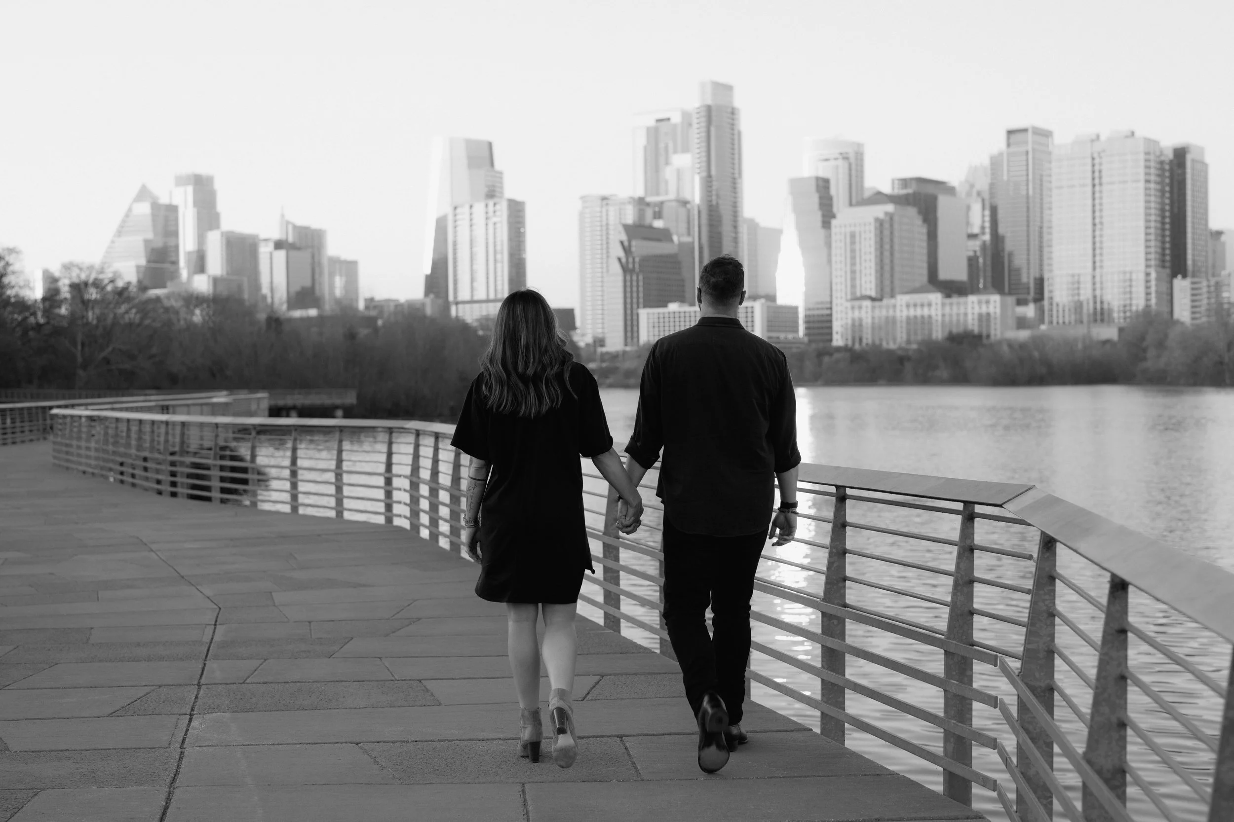 Couple holds hands for boardwalk engagement photos at Lady Bird Lake in Austin