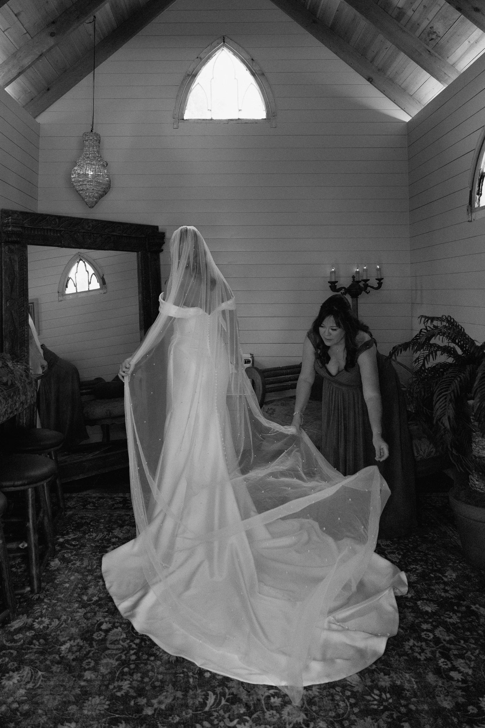 Bride in a long veil having her train adjusted in the getting-ready room at Chapel Dulcinea