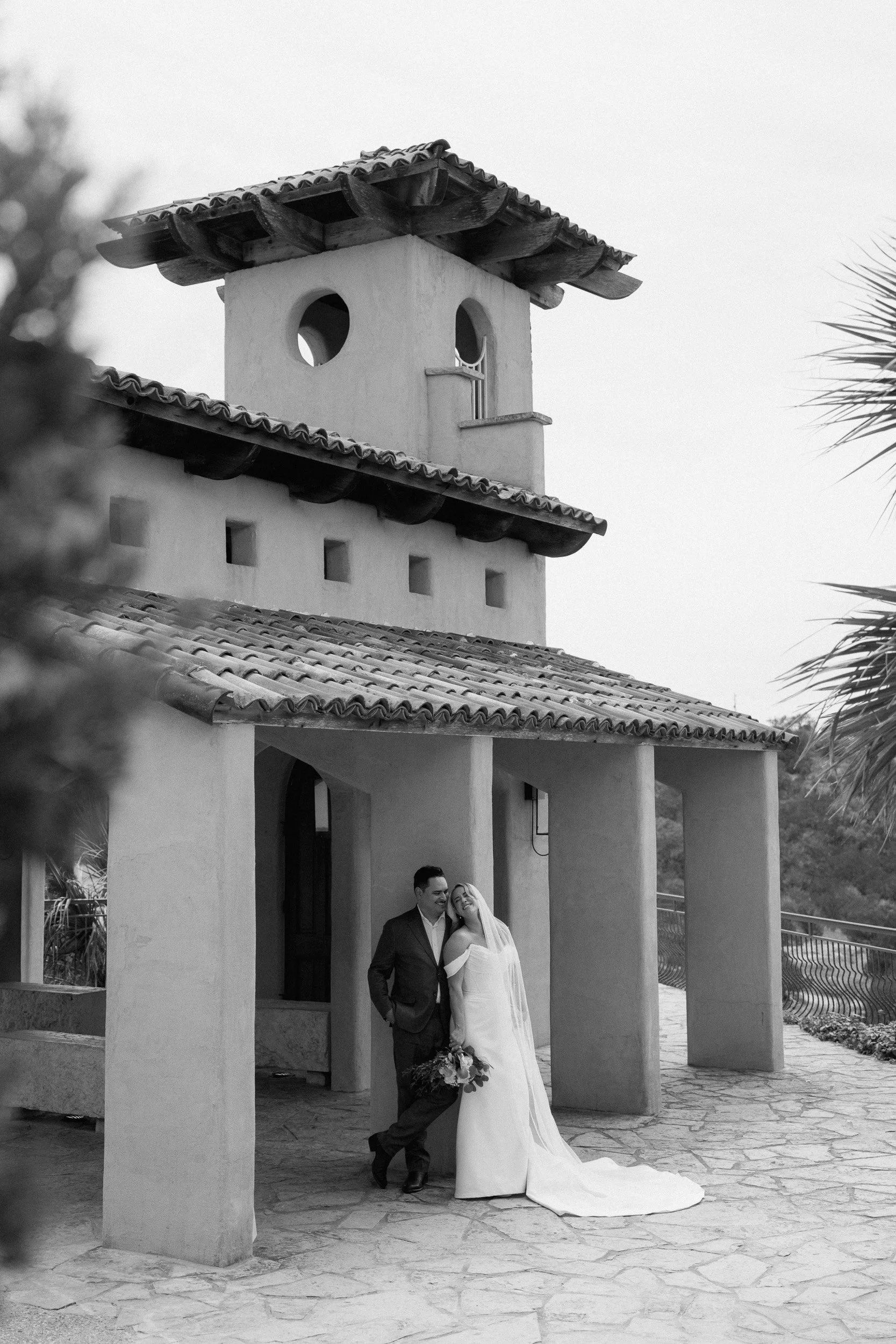The tiered chapel tower rises above the couple leaning together below, in black and white