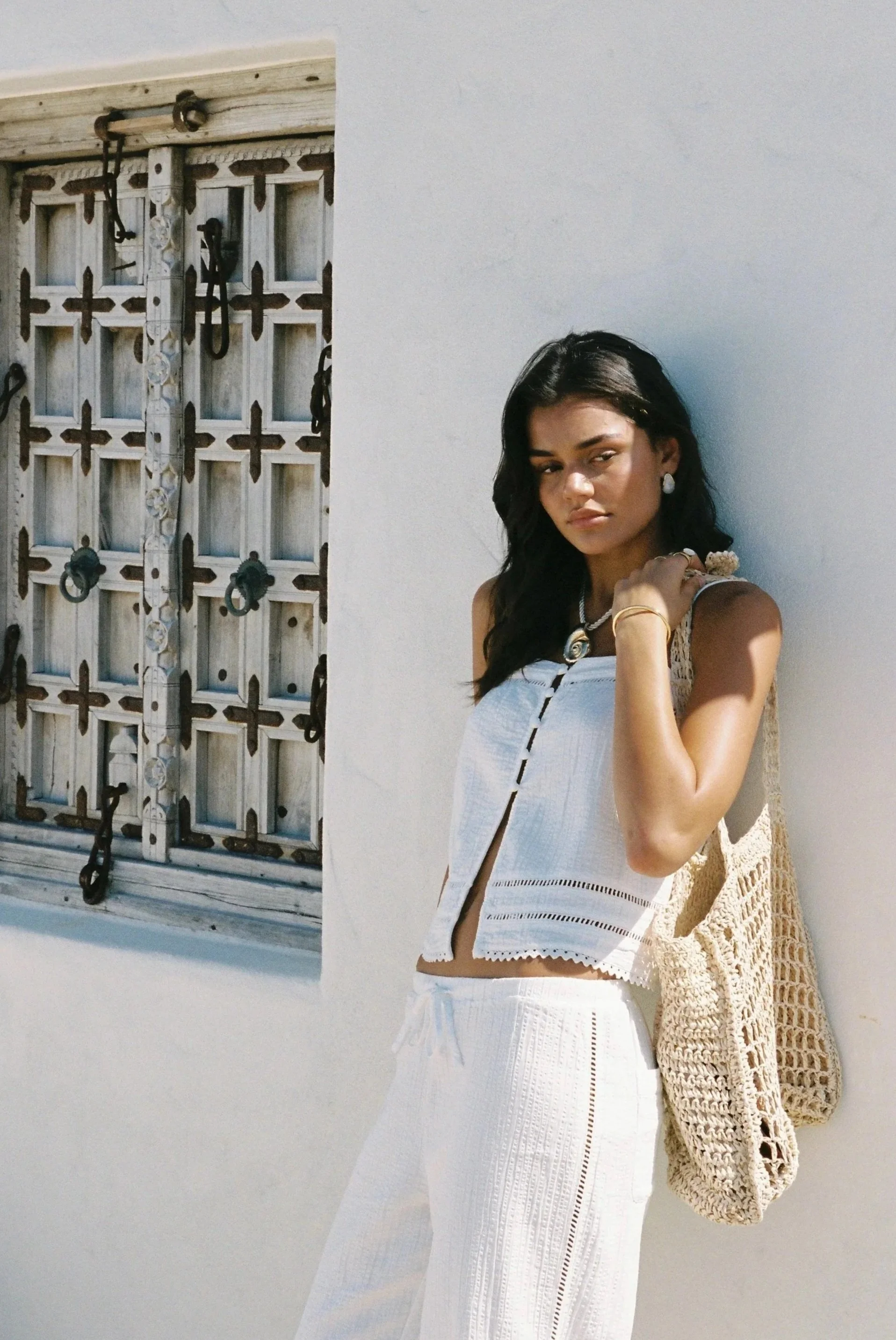 A girl against a wall wearing a white two-piece Rhythm set