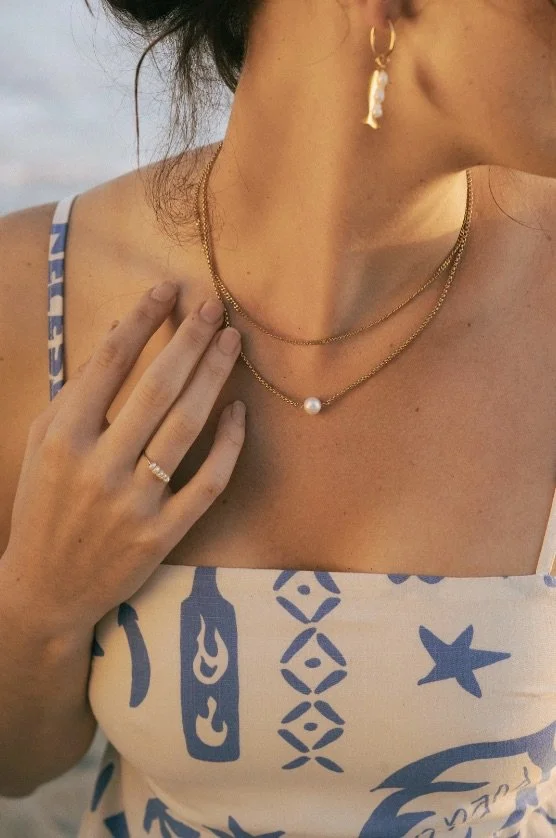 A girl at the beach wearing a pearl necklace and ring from Salty Cali Jewelry 
