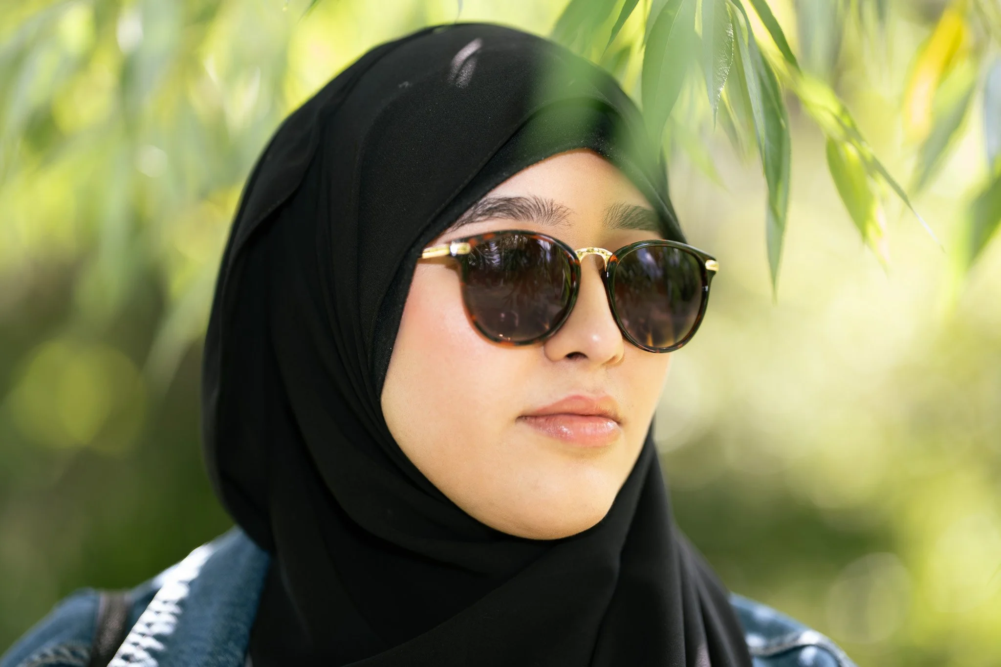 A woman wearing glasses and standing under a tree
