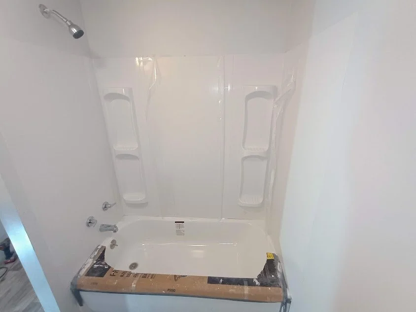 Bathroom with a bathtub surrounded by a white shower curtain and built-in corner shelves, with a showerhead mounted on the wall.