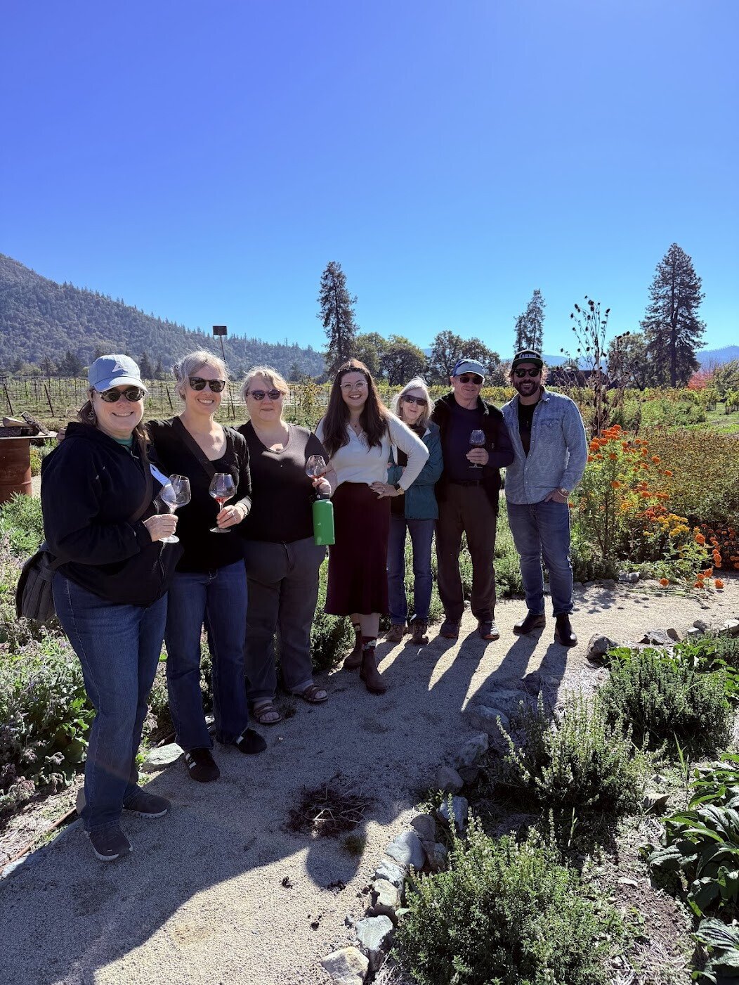 Applegate wine tour group poses for a picture with certified wine educator Faith, enjoying oregon wine tours and lodging.