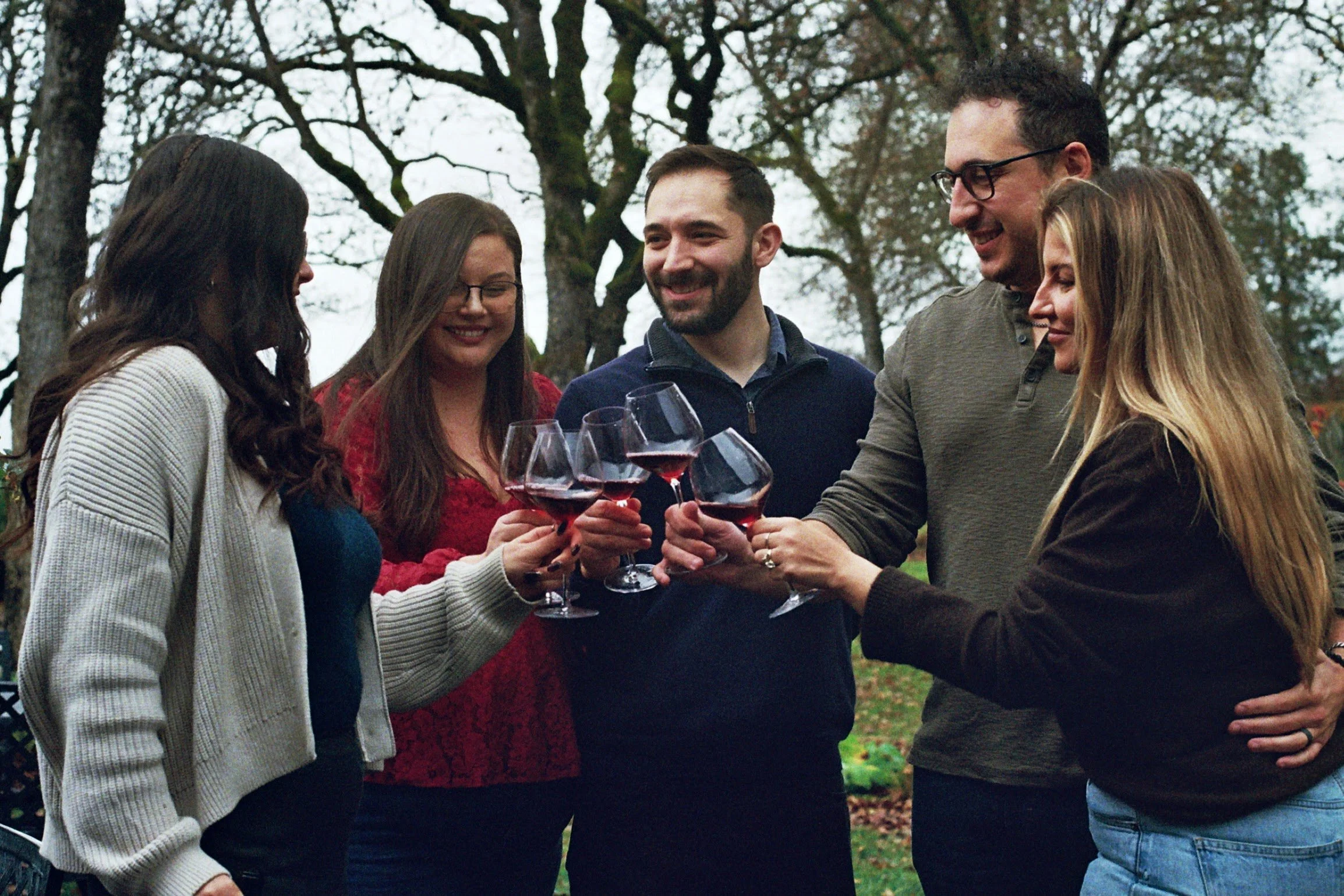 A group of four friends with their tour guide cheers glasses of red wine in the Rogue Valley.