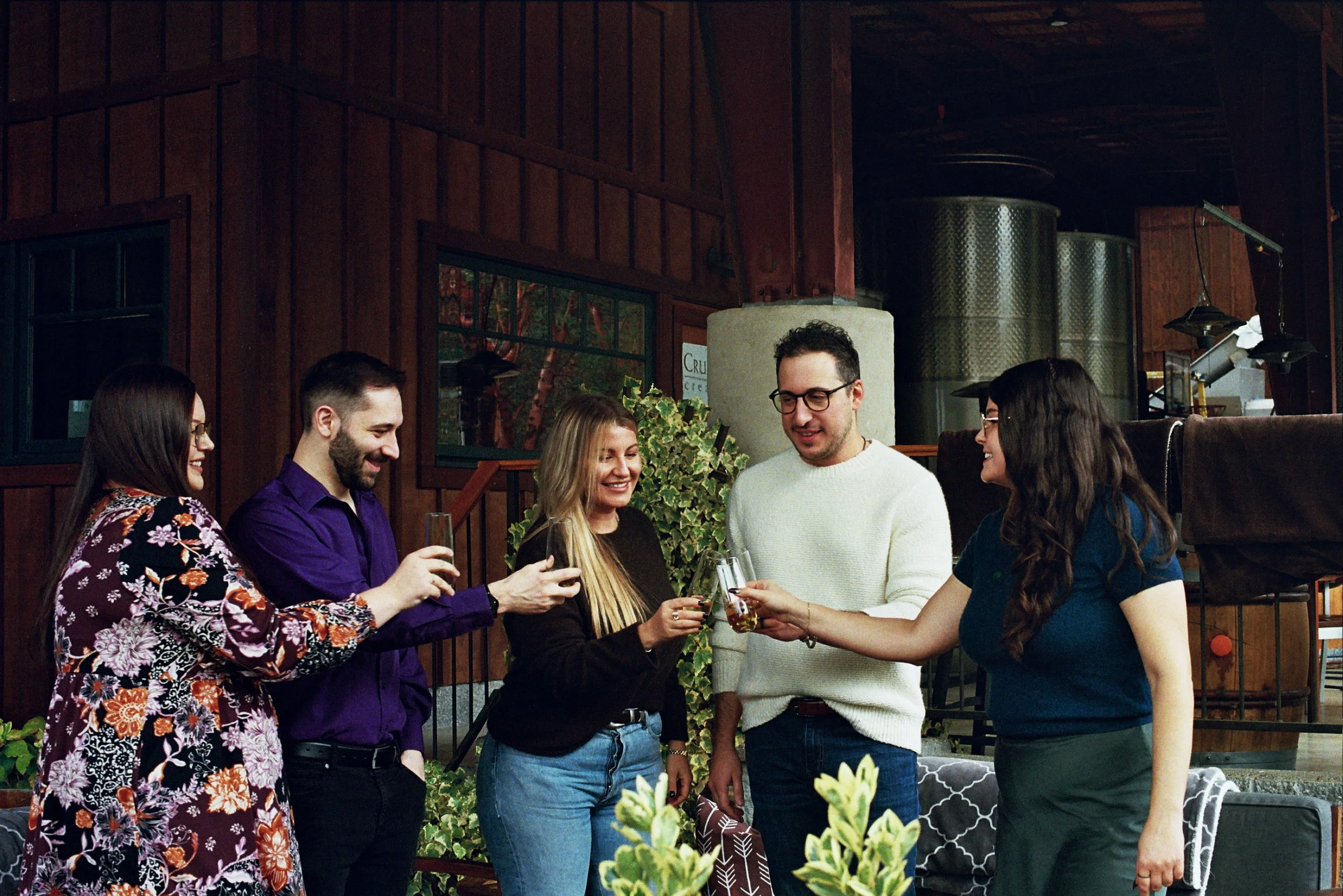 A group of five wine tasting guests cheers glasses of bubbles at a Rogue Valley tasting room.