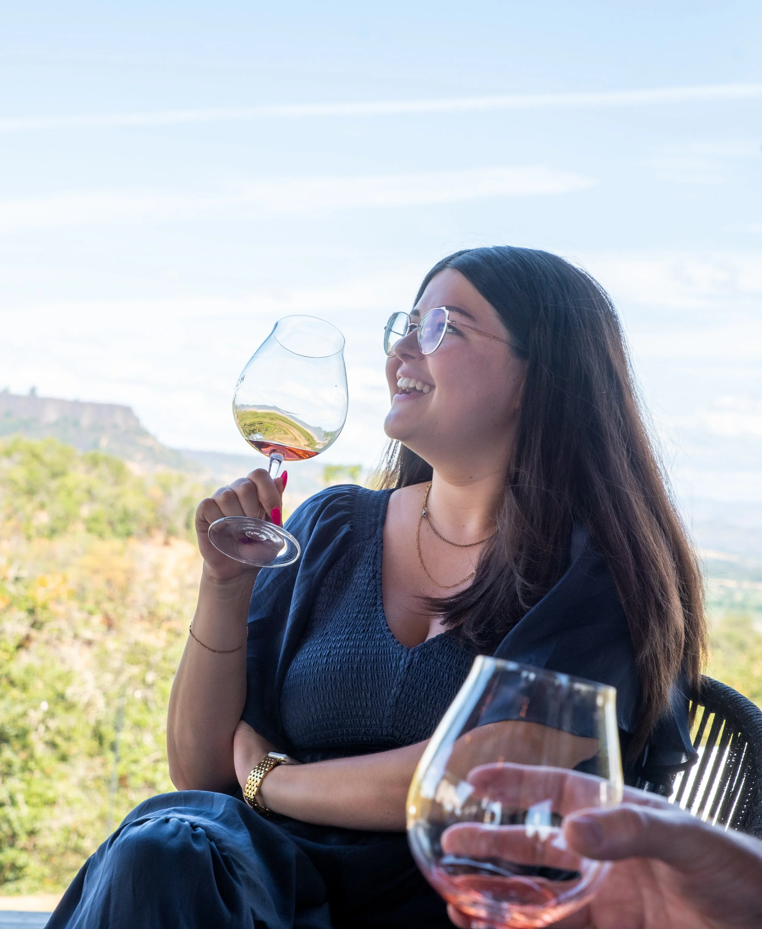 WSET 3 Certified Wine Educator Faith Lemire-Baeten smiling with a glass of wine in hand on a Rogue Valley Wine Tour, wine tours Southern Oregon.