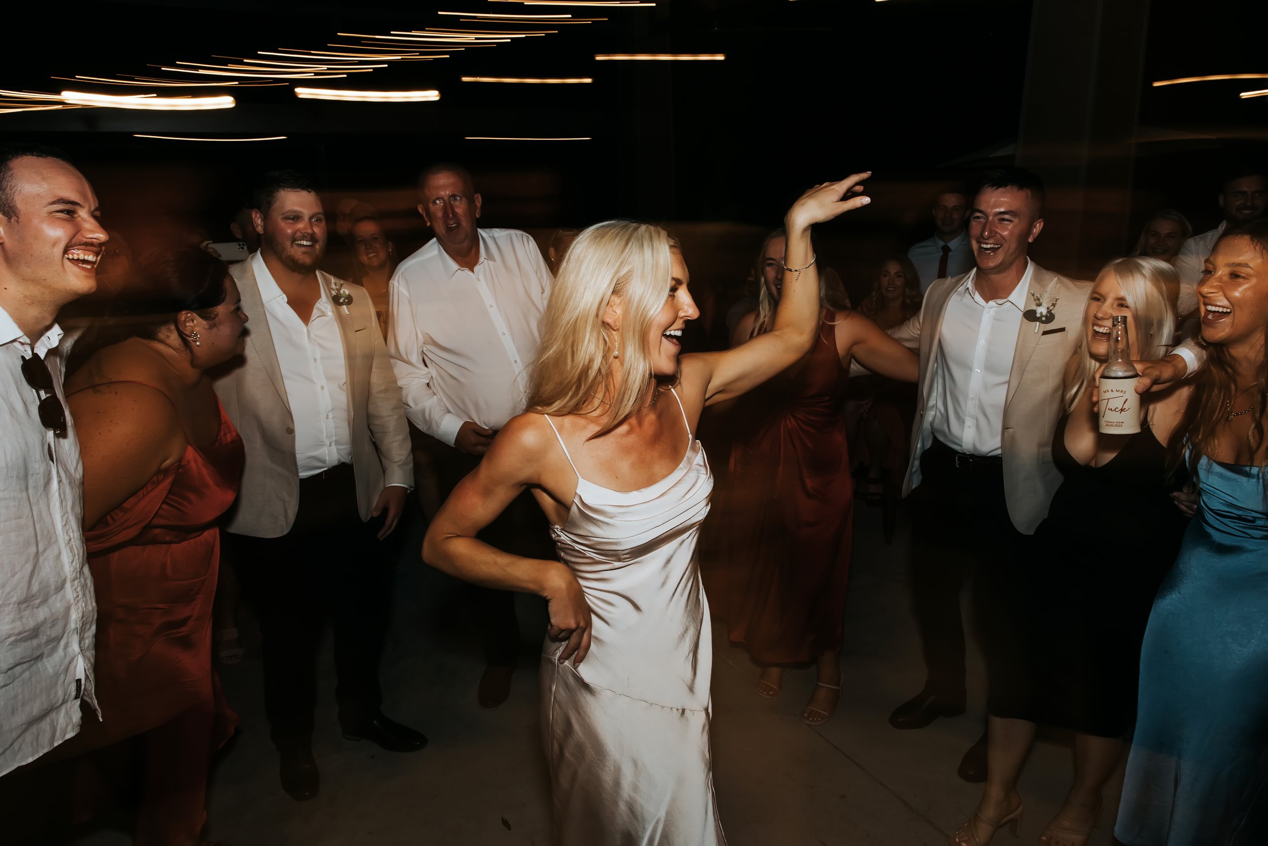 People dancing and laughing at a celebration or party indoors with dim lighting