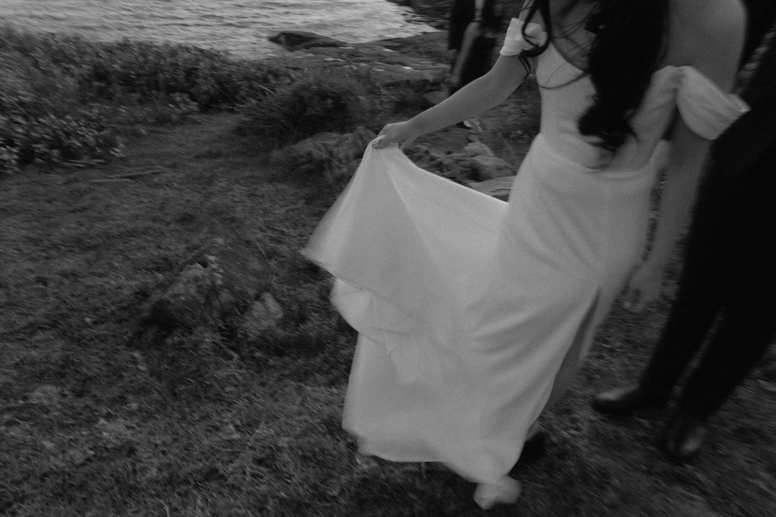 Woman's arm holding a white cloth or bag outside, grassy field in the background, black and white photo.
