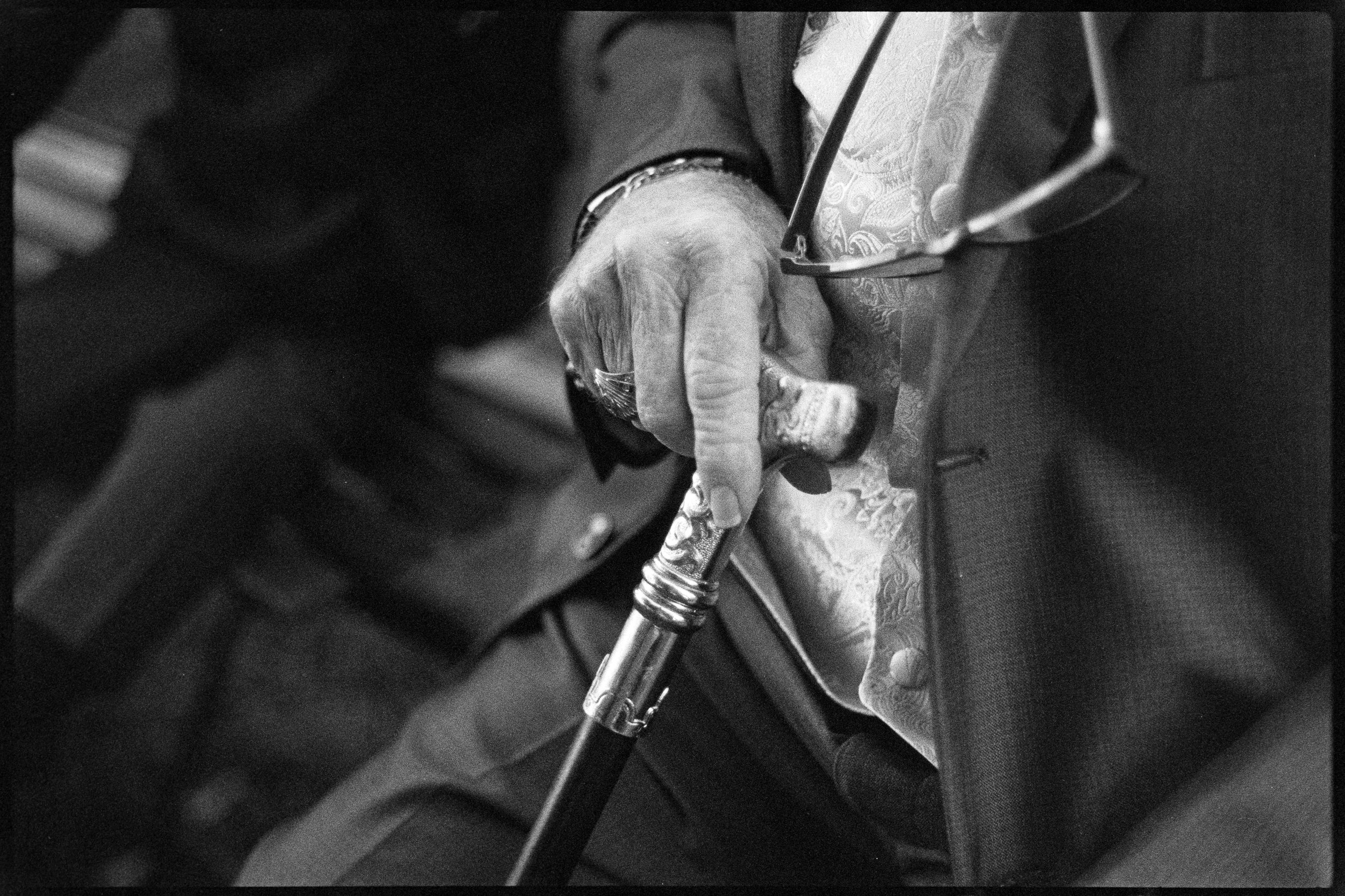 Close-up of an elderly person's hand holding a tool, with musical notes on the fabric of the person's clothing, suggesting they are playing the violin.