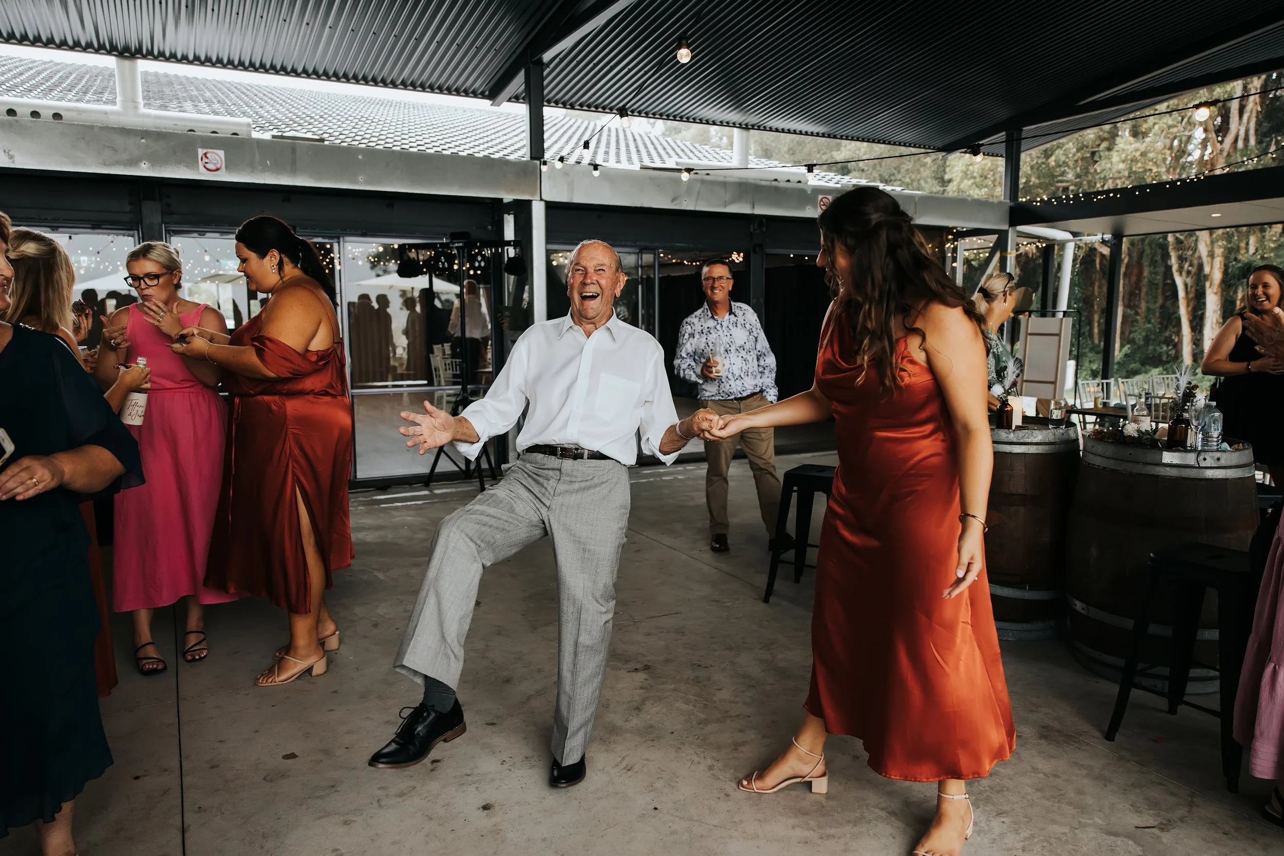 People dancing and socializing at an outdoor event with string lights and a covered patio.