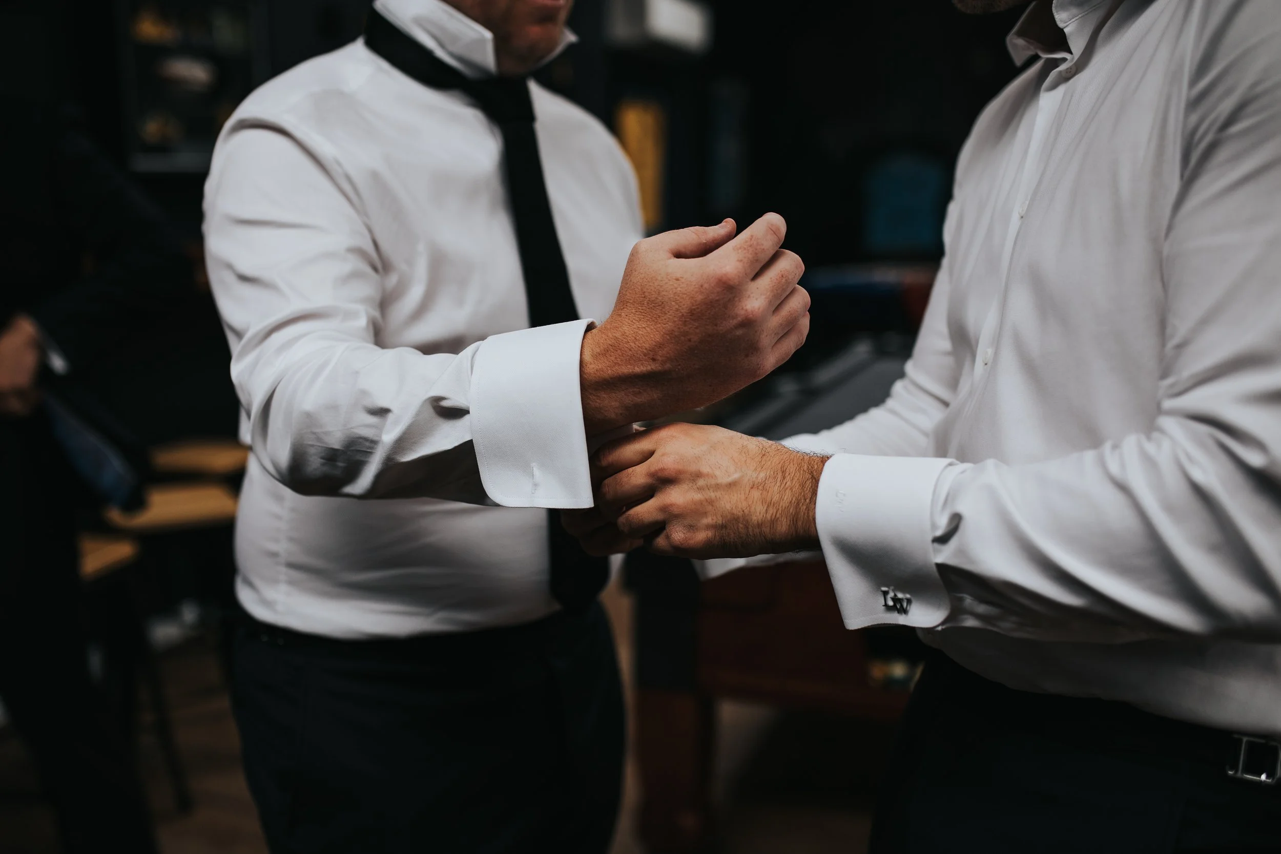 Two men in dress shirts shaking hands at a business meeting or social gathering.