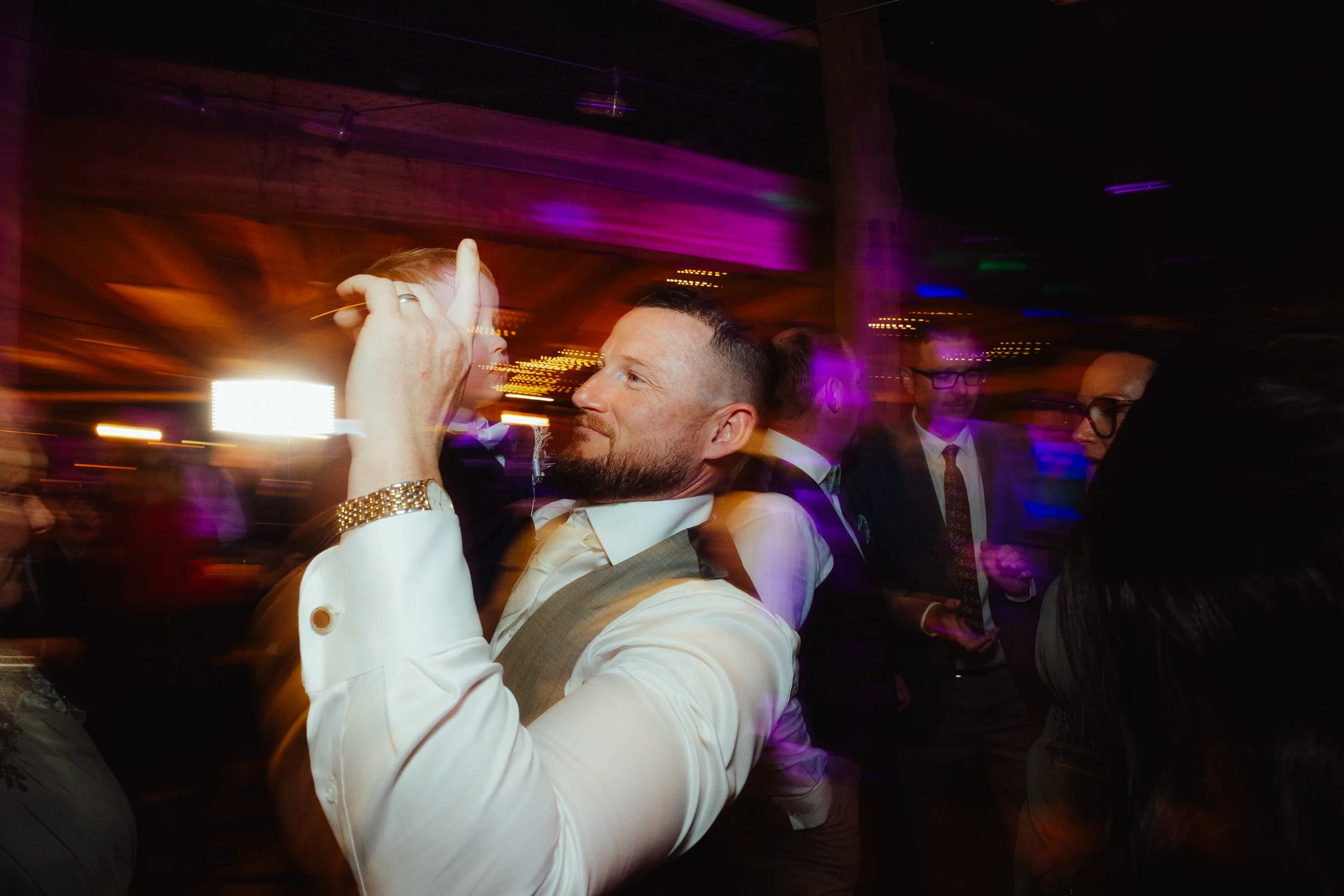 People dancing at a lively party with colorful lights and motion blur, enjoying the music.