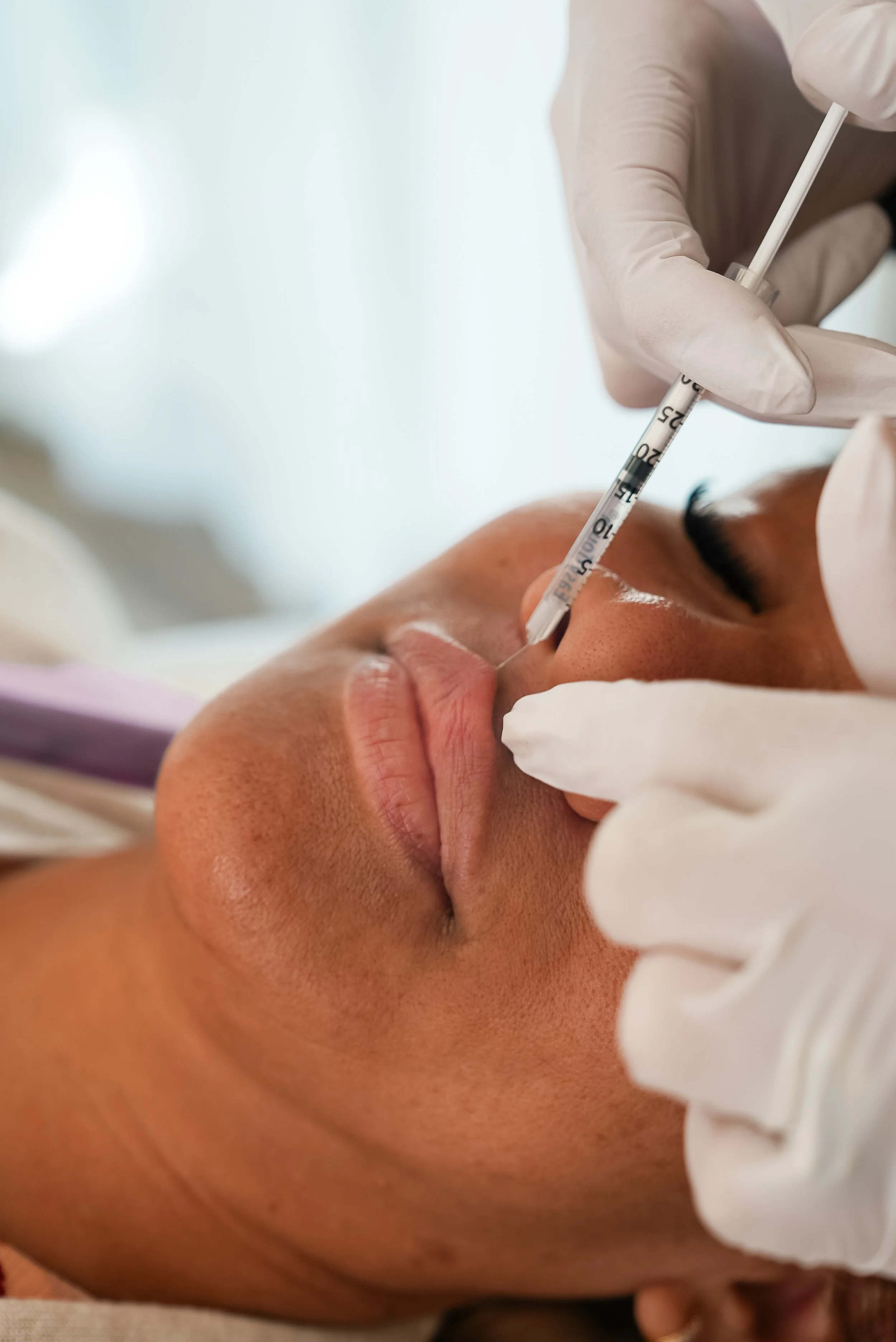 A person receiving an injection in their nose from a healthcare professional wearing gloves.