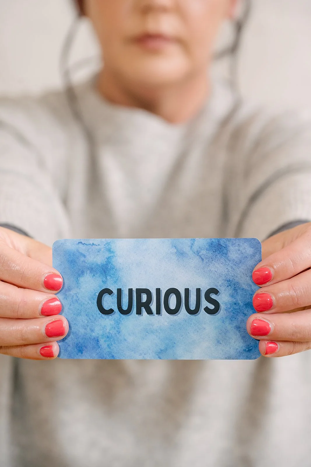 Woman holding a card with the word ‘Curious’