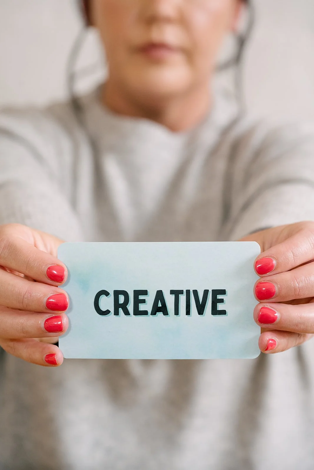 Woman holding a card with the word ‘Creative'