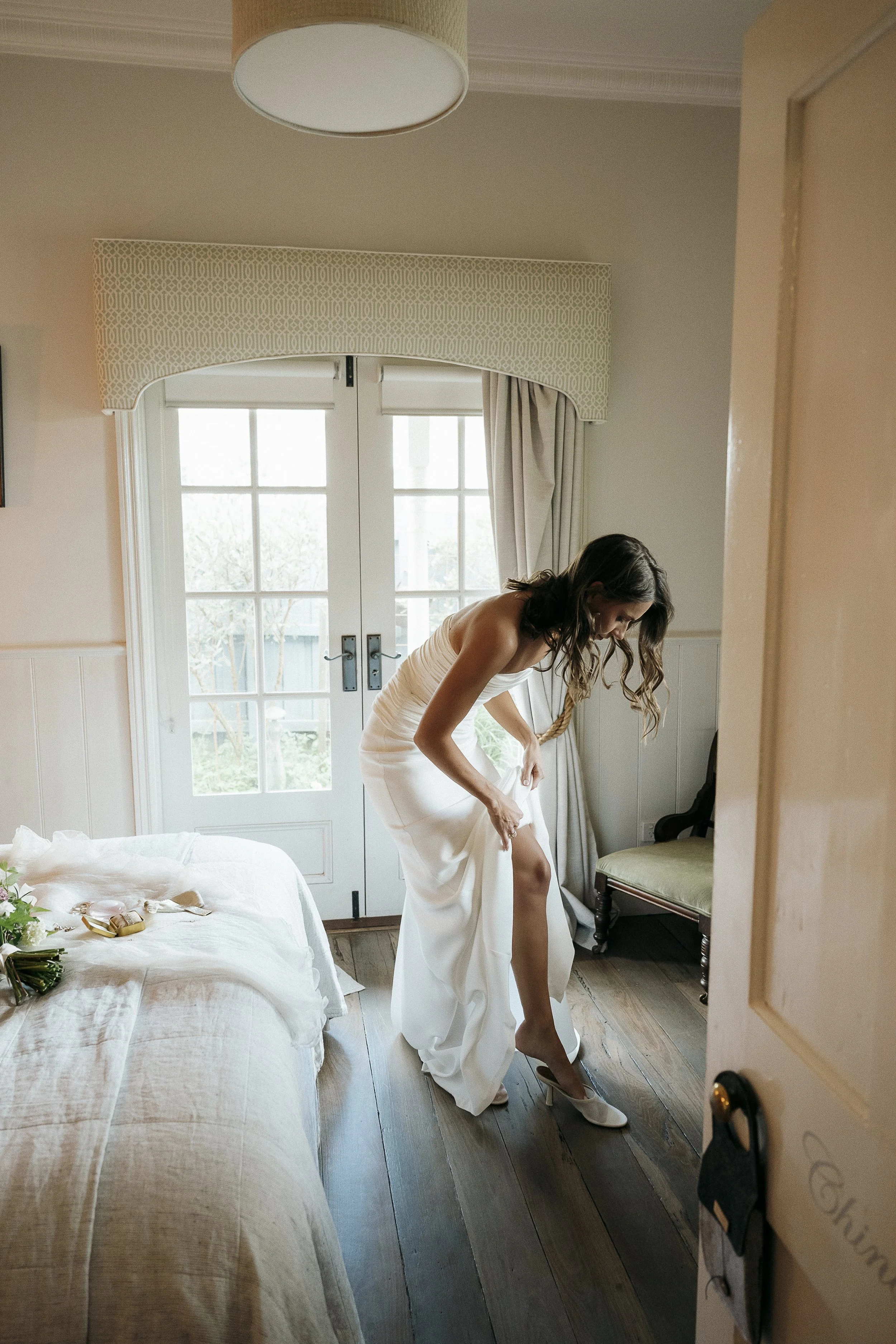 Bride getting ready in the Miner’s Cottage at Acre of Roses, wearing a modern two-piece bridal outfit.