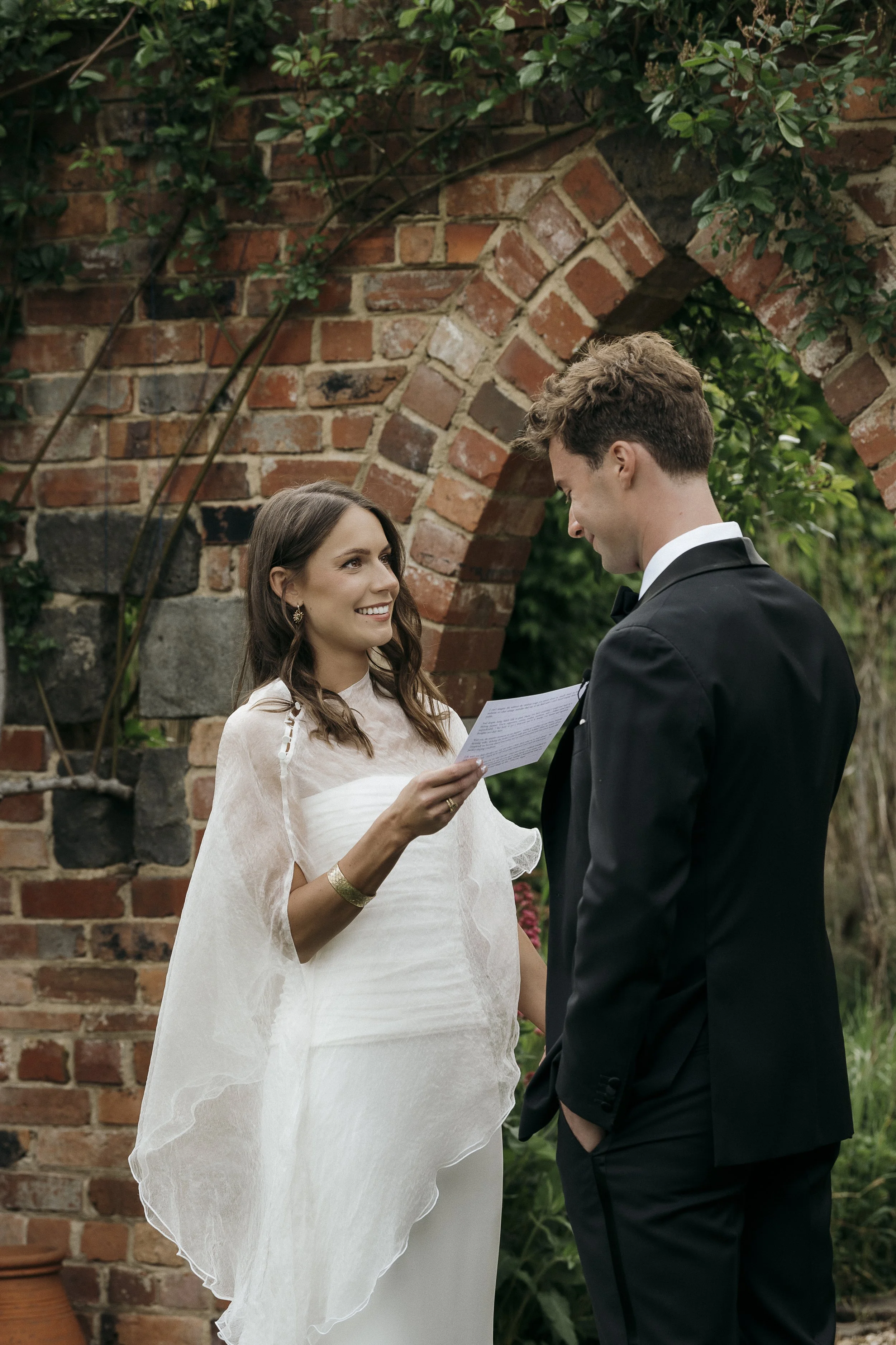 Couple exchanging vows in front of the folly during their Acre of Roses elopement.
