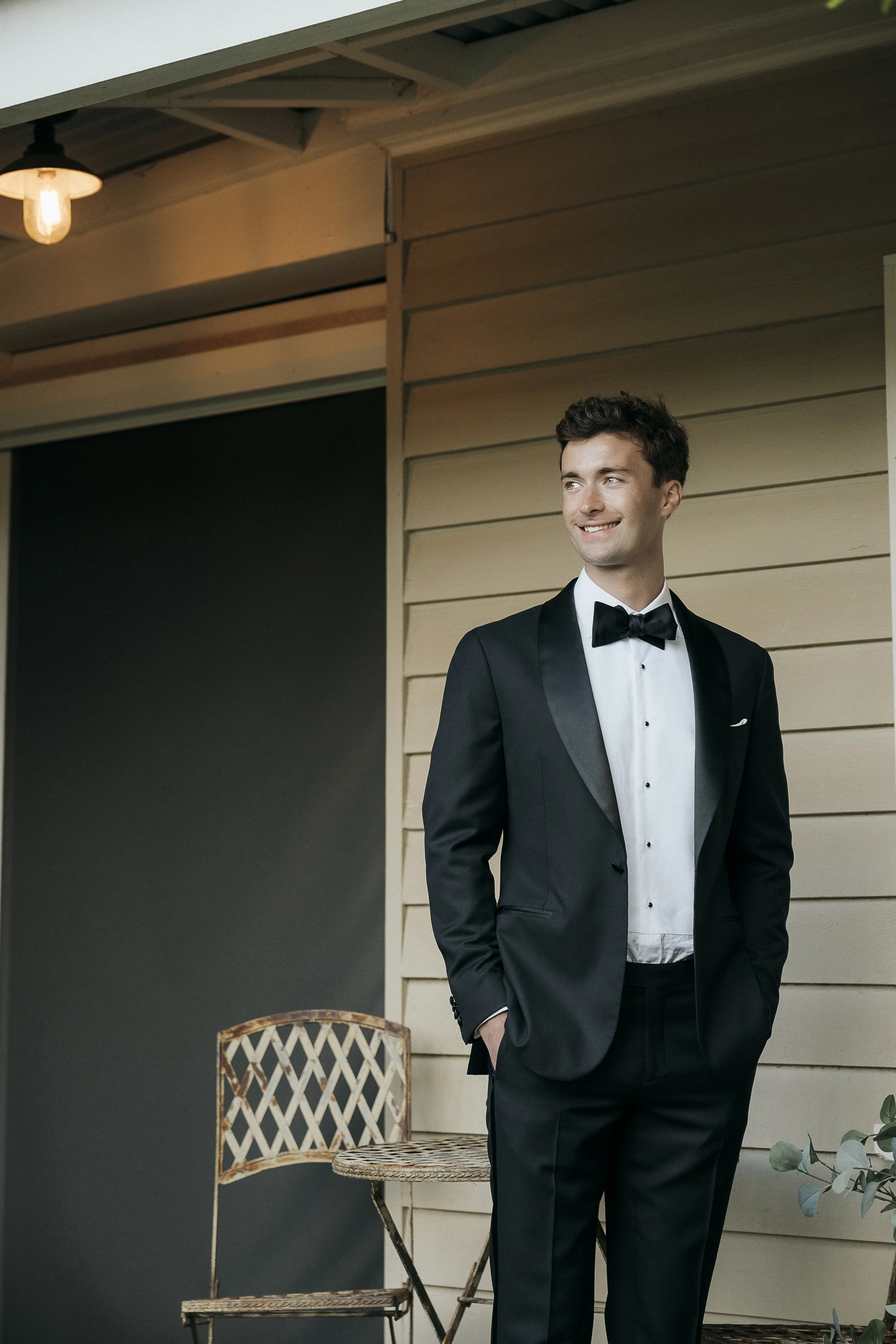 Portrait of the groom wearing a tux with satin side stripe pants and bow tie