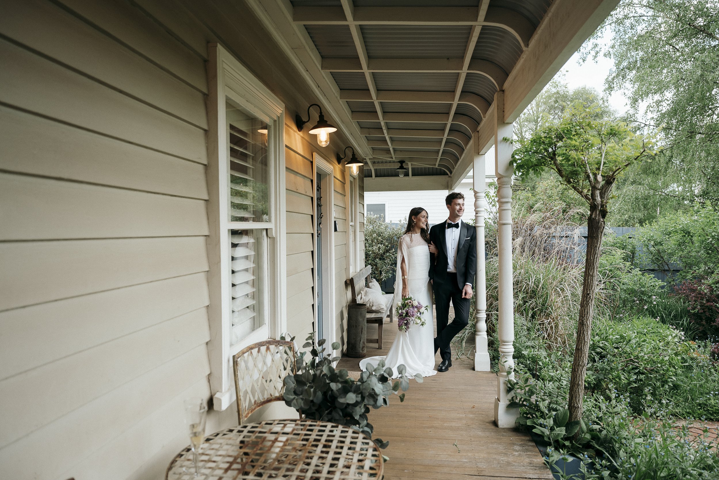 Final wide shot of the couple in the Acre of Roses on the front verandah of the Minors Cottage as newlyweds