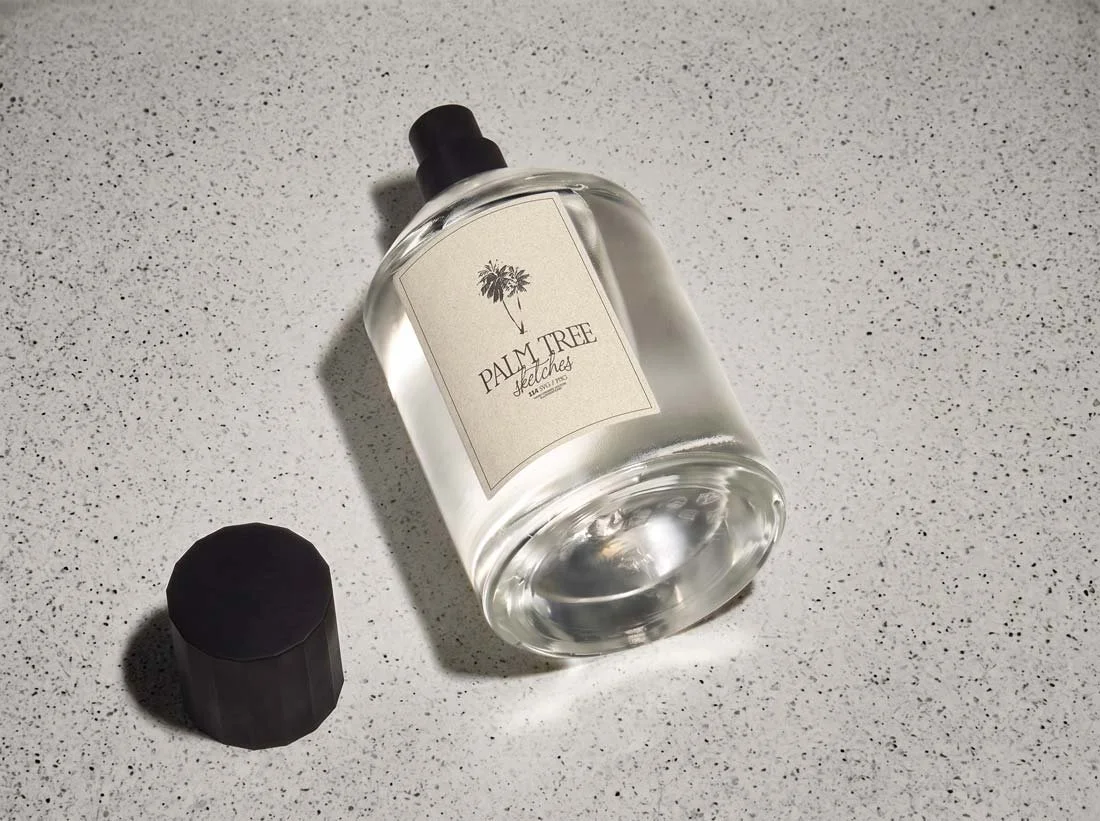 Minimalist perfume bottle mockup featuring a palm tree illustration on a clean, light background.