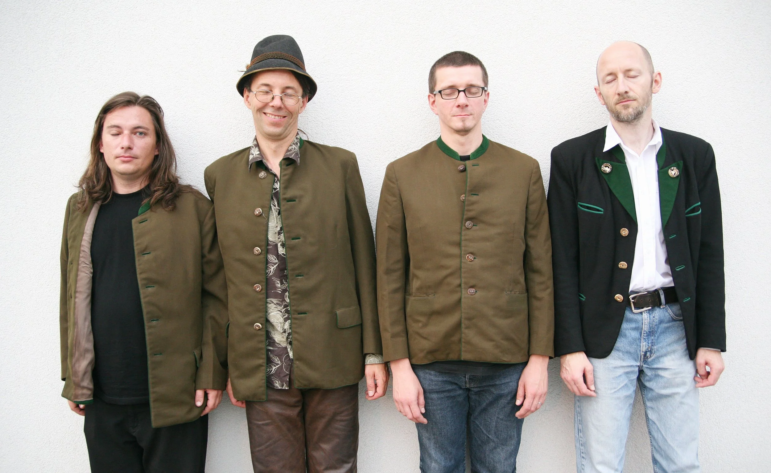 4 Herren in Tracht stehen vor einer weißen Wand und haben die Augen geschlossen