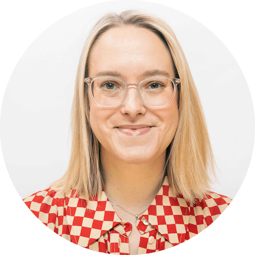 Ella has shoulder length, straight, blonde hair and hazel eyes. She is wearing glasses and a smile