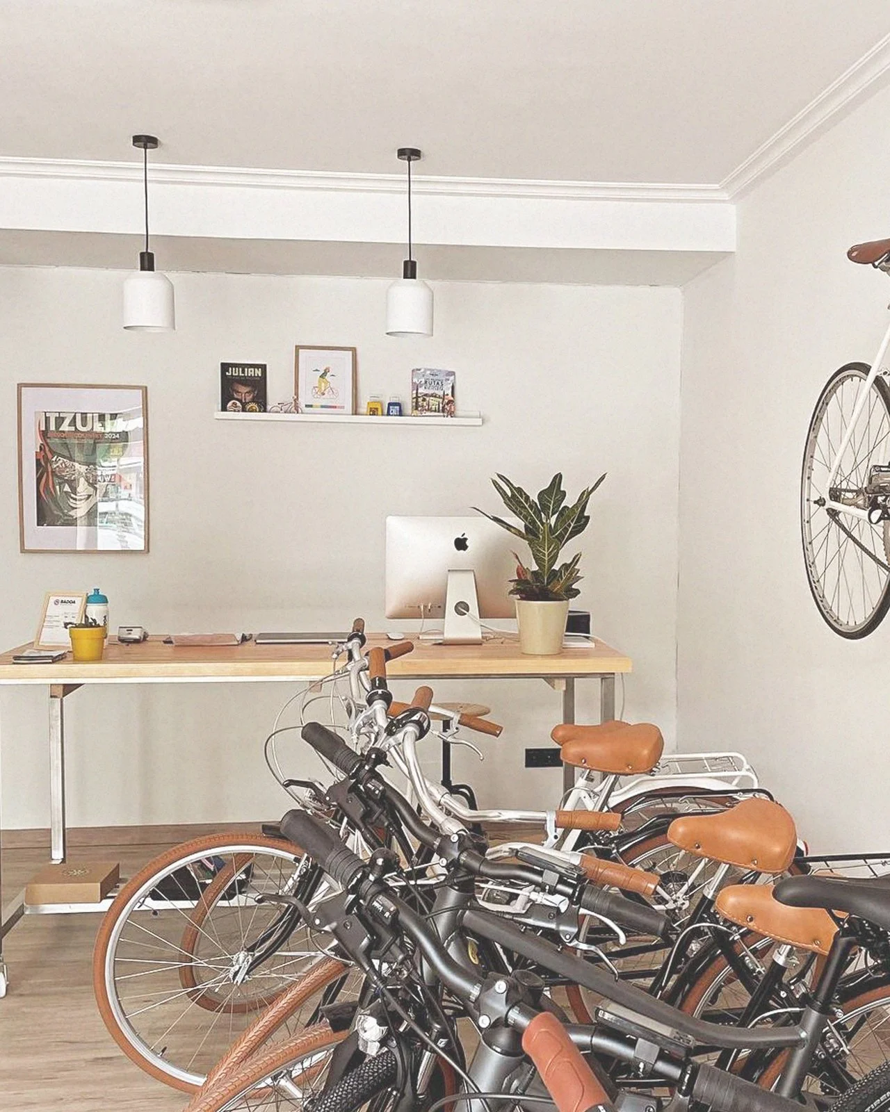 Interior de una oficina con varias bicicletas estacionadas y un escritorio con una computadora y una planta en una mesa